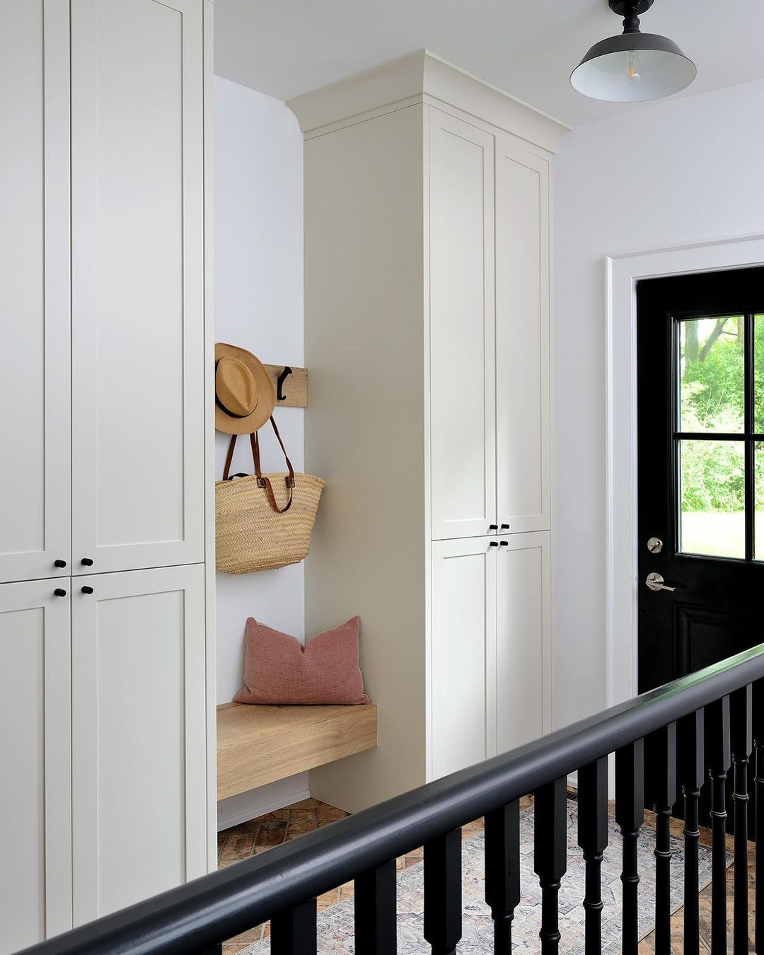 Ein Abstellraum in einem Eingangsbereich mit raumhohen Schränken, einem schwebenden Holzregal und einer hängenden Garderobe.