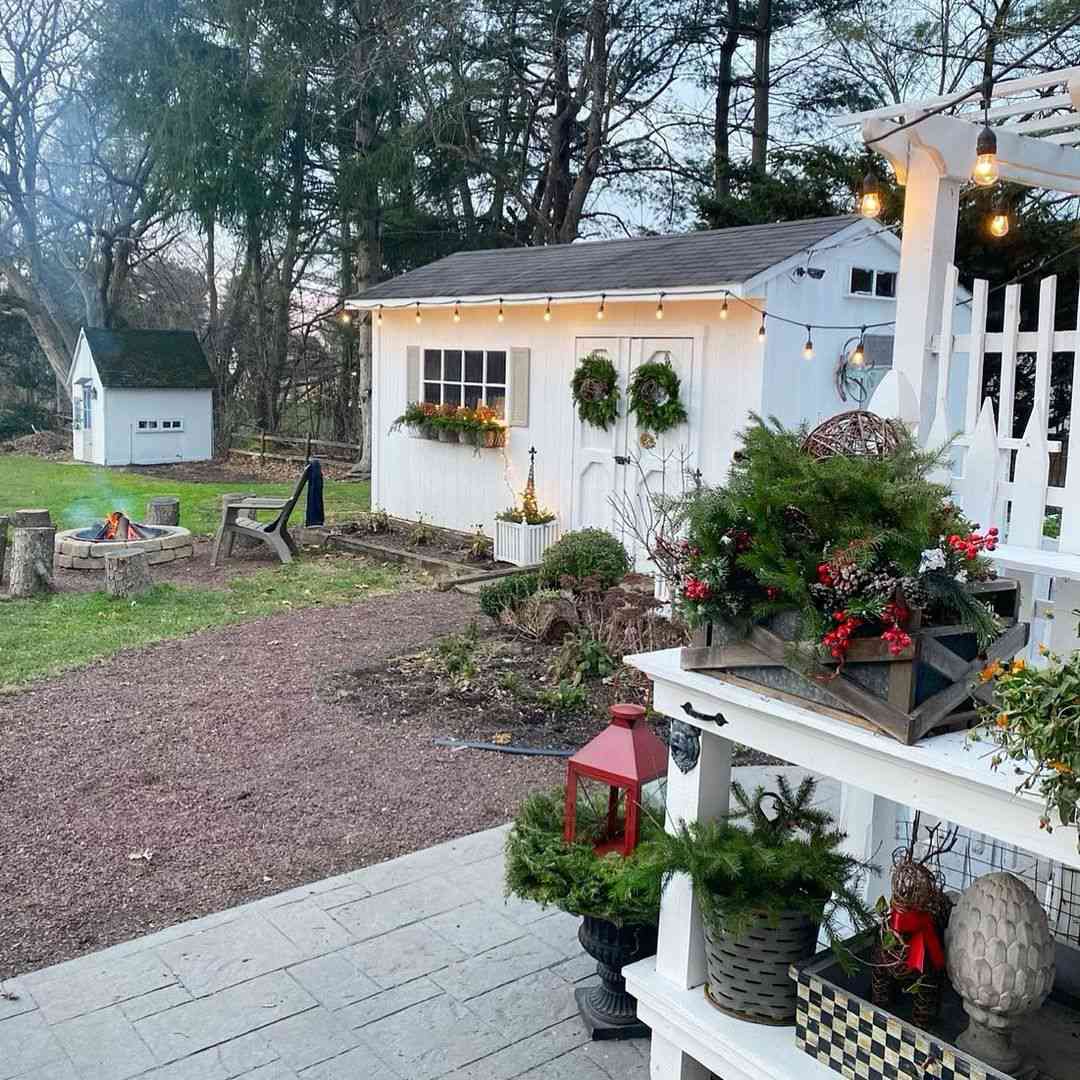 Ein weißer, mit Weihnachtsgrün geschmückter Schuppen im Landhausstil.