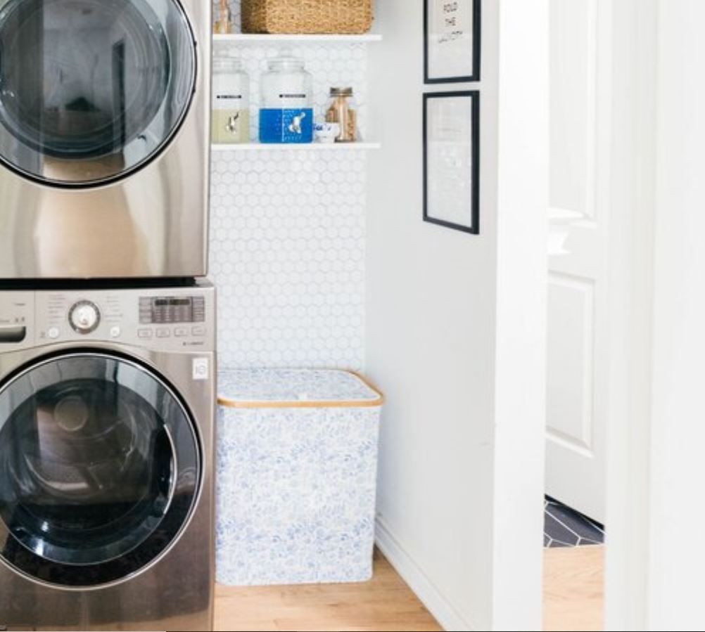 Wäscheschrank mit gestapelter Waschmaschine und Trockner und sechseckigen Wandfliesen.