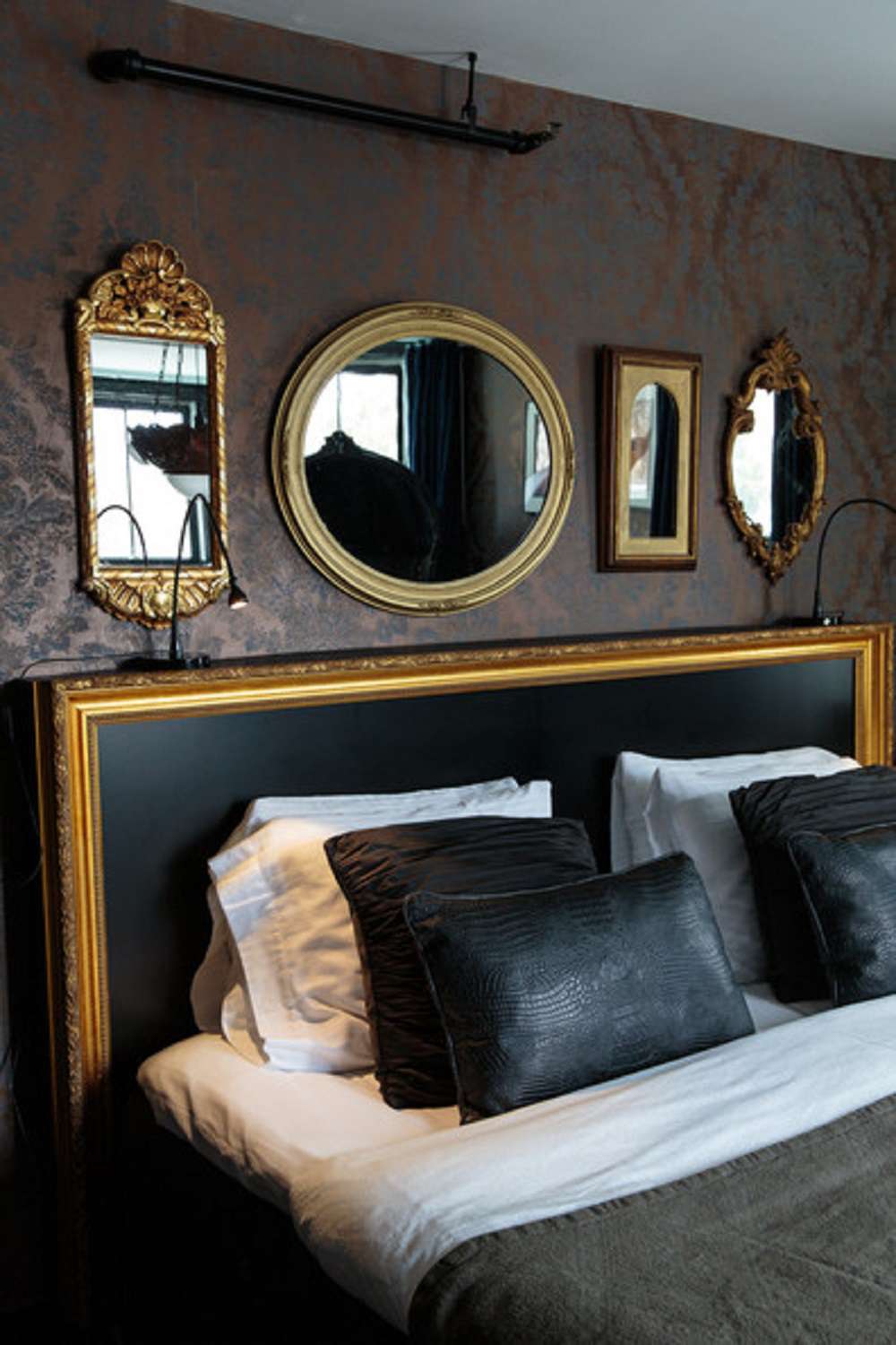 Schlafzimmer mit goldgerahmten Spiegeln über goldgerahmtem Kopfteil