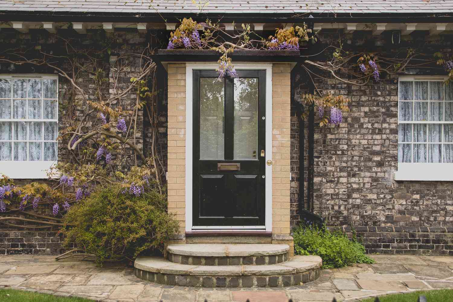 puerta de entrada con flores moradas en una casa de ladrillo