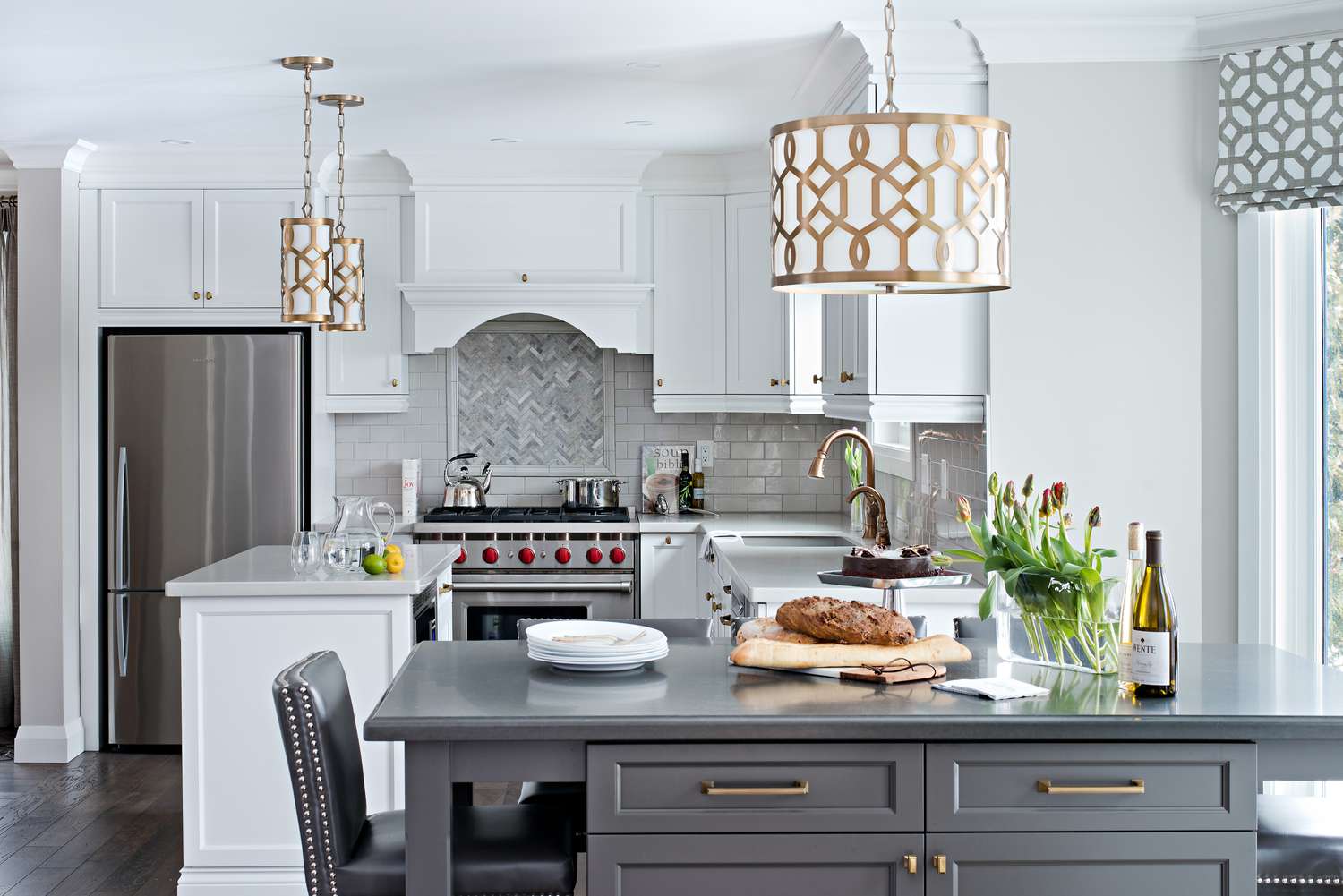 Moderna cocina blanca con isla gris, y una luz colgante blanca/latón colgando encima