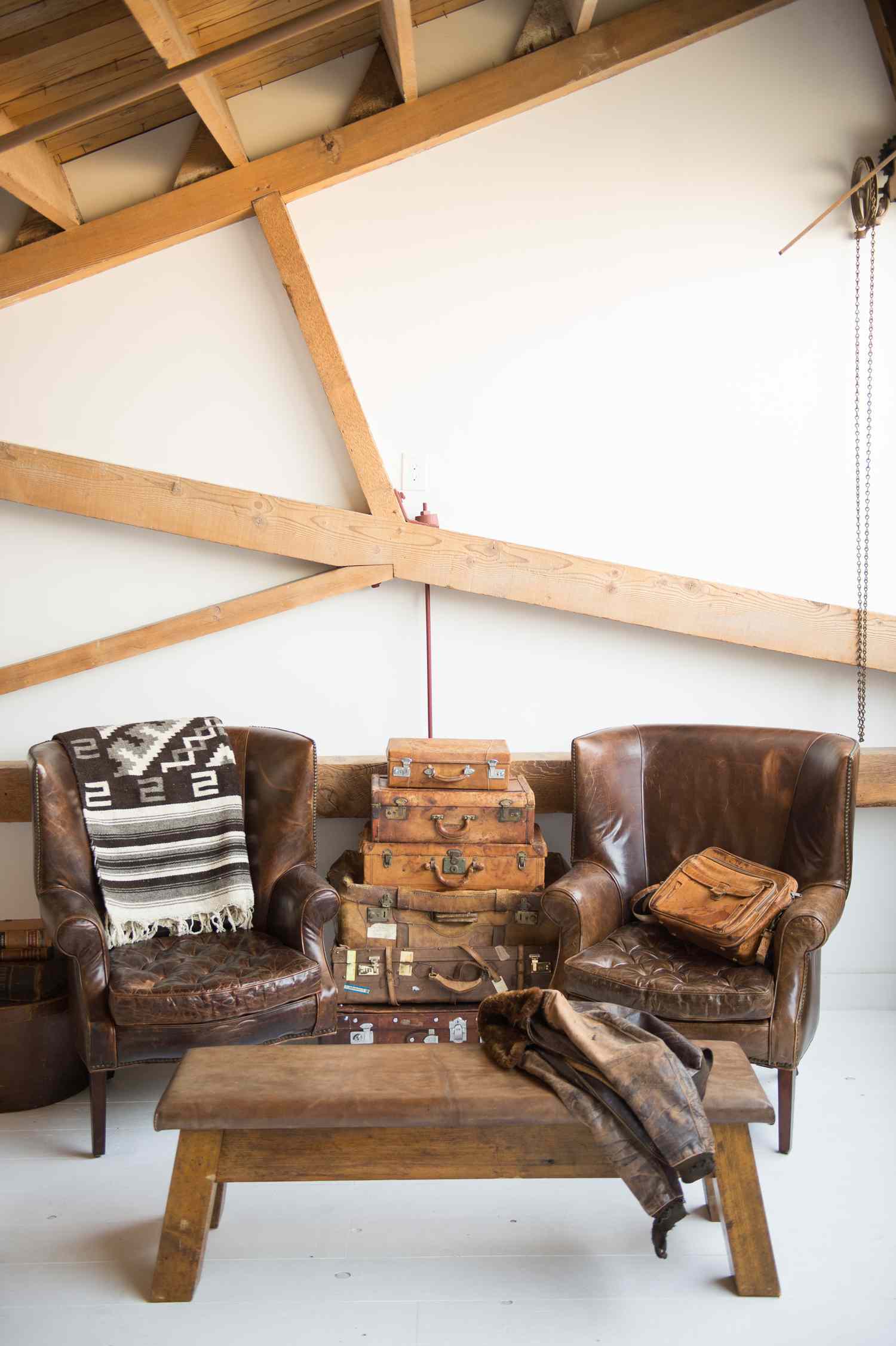 Chambre rustique avec fauteuils en cuir et pile de valises vintage au milieu