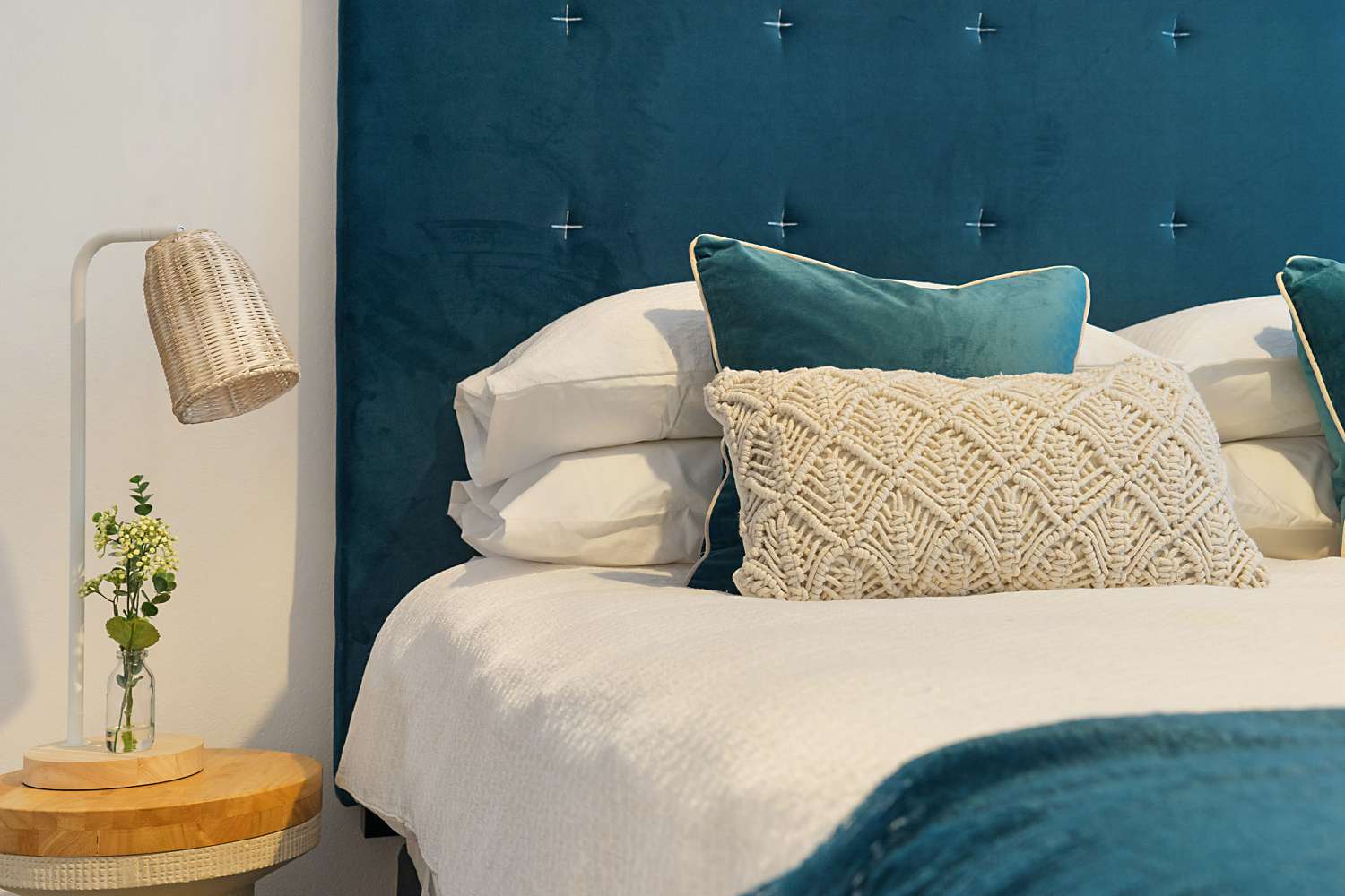 Bett mit blauer Bettwäsche und gepolstertem Kopfteil