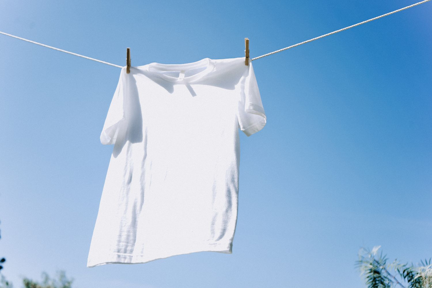 Weißes Hemd an der Wäscheleine vor blauem Himmel