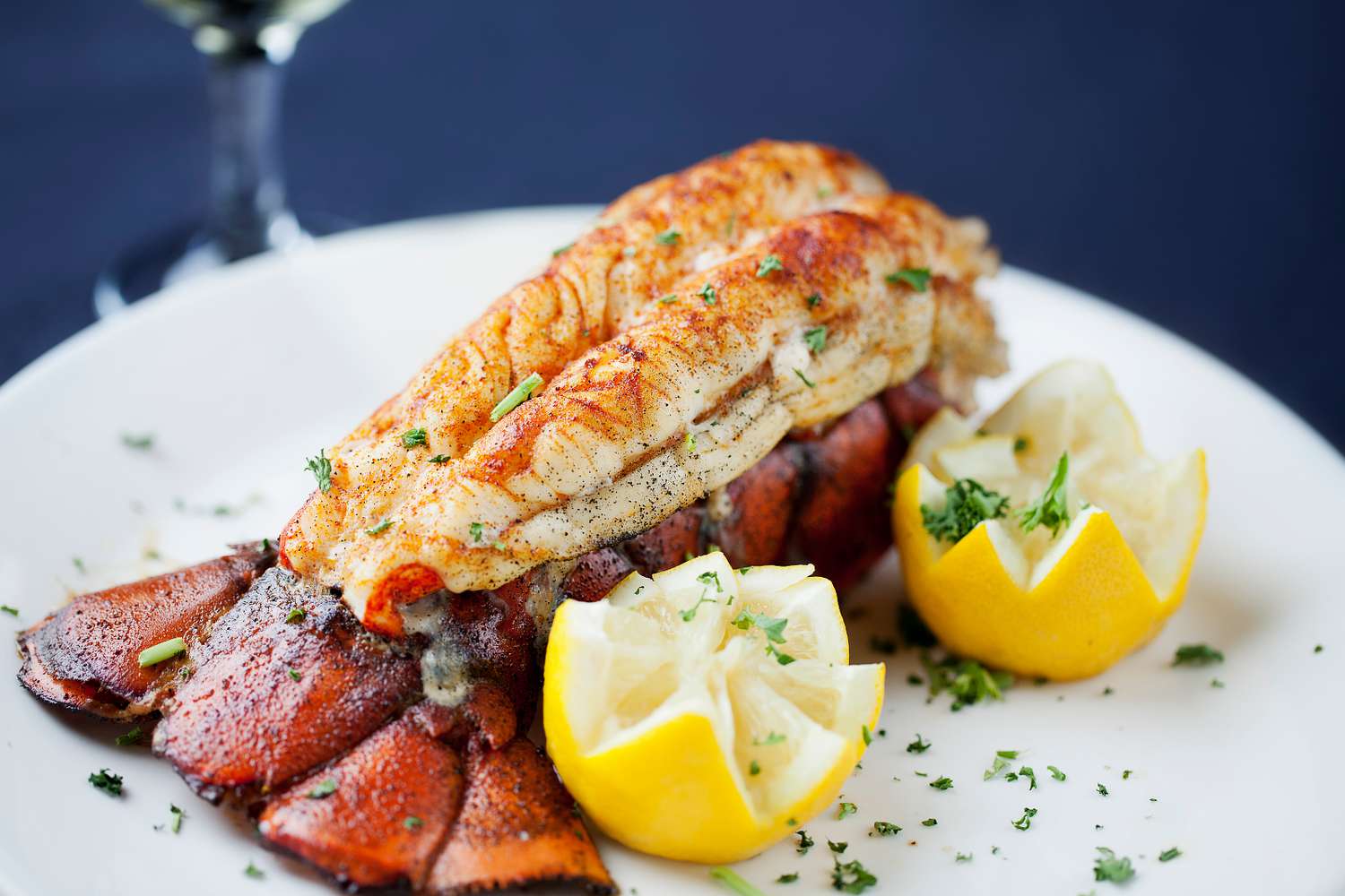 Queue de homard cuite avec deux moitiés de citron sur une assiette blanche