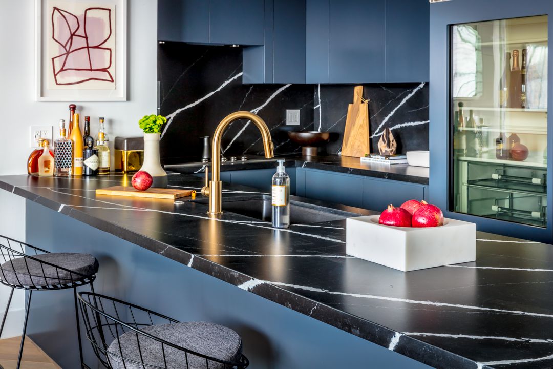 black and blue kitchen with black marble countertops and backsplash