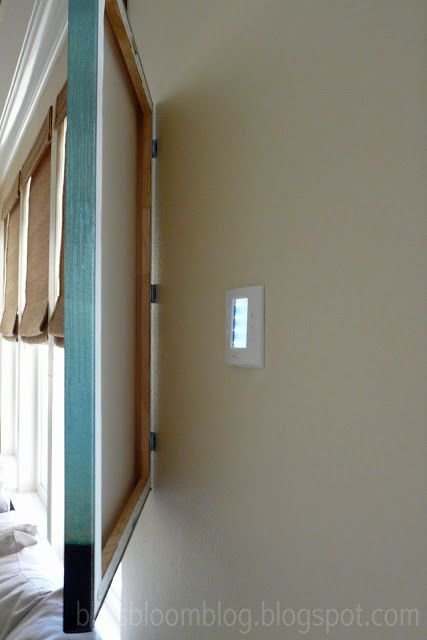 Pintura abatible abierta en la pared con un panel termostato oculto detrás
