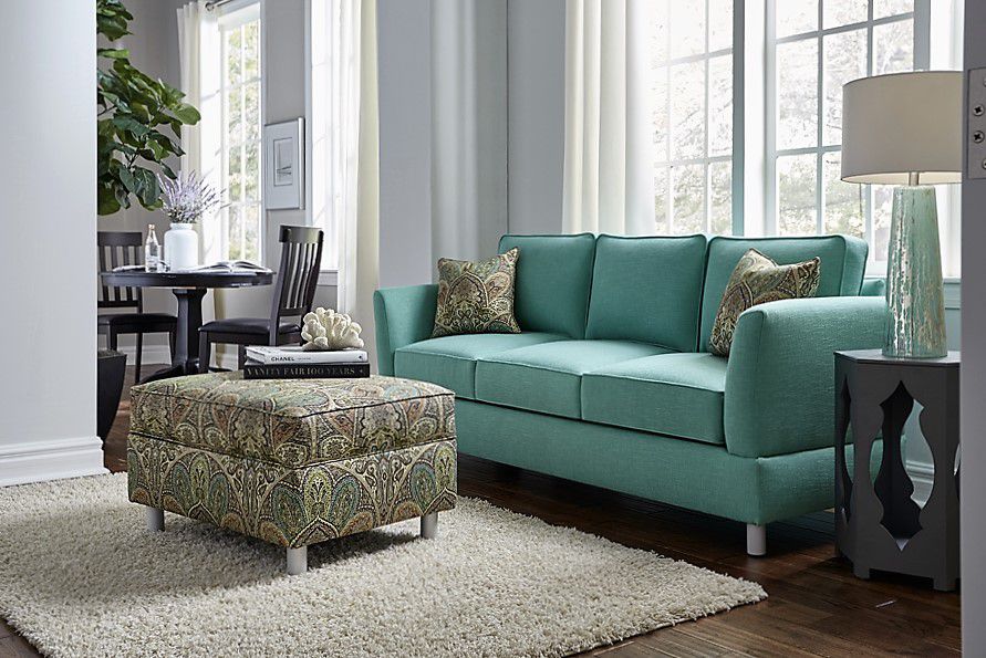 Sala com sofá de três lugares azul-esverdeado e pufe estampado