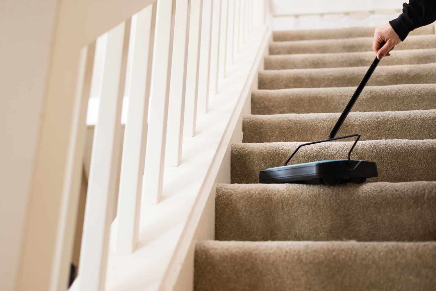 Manual carpet sweeper running against carpetted staircase steps