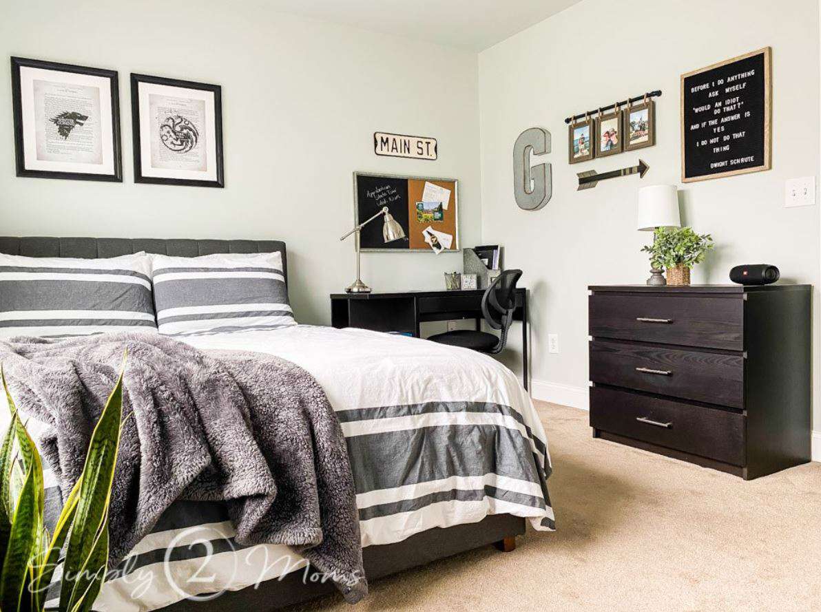 Dormitorio de chico adolescente con paredes neutras en gris claro y cama de matrimonio con ropa de cama a rayas.