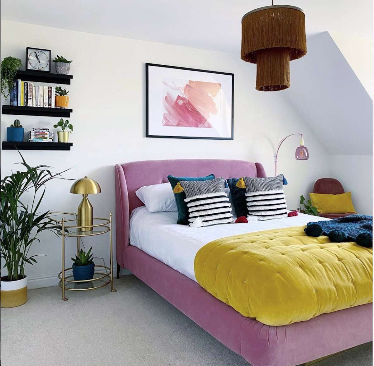chambre à coucher avec murs blancs, cadre de lit violet clair, édredon jaune, accents de verre or et violet