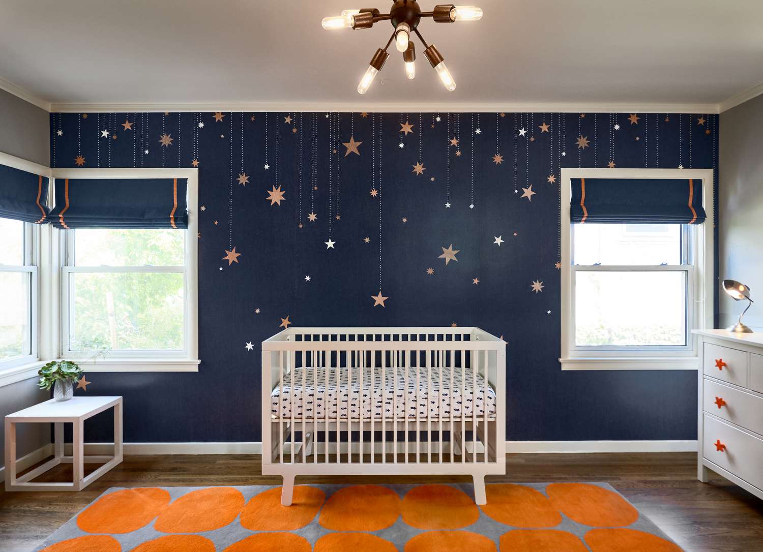 Ein Kinderzimmer in Marineblau, Orange und Grau mit Sternen an der Wand