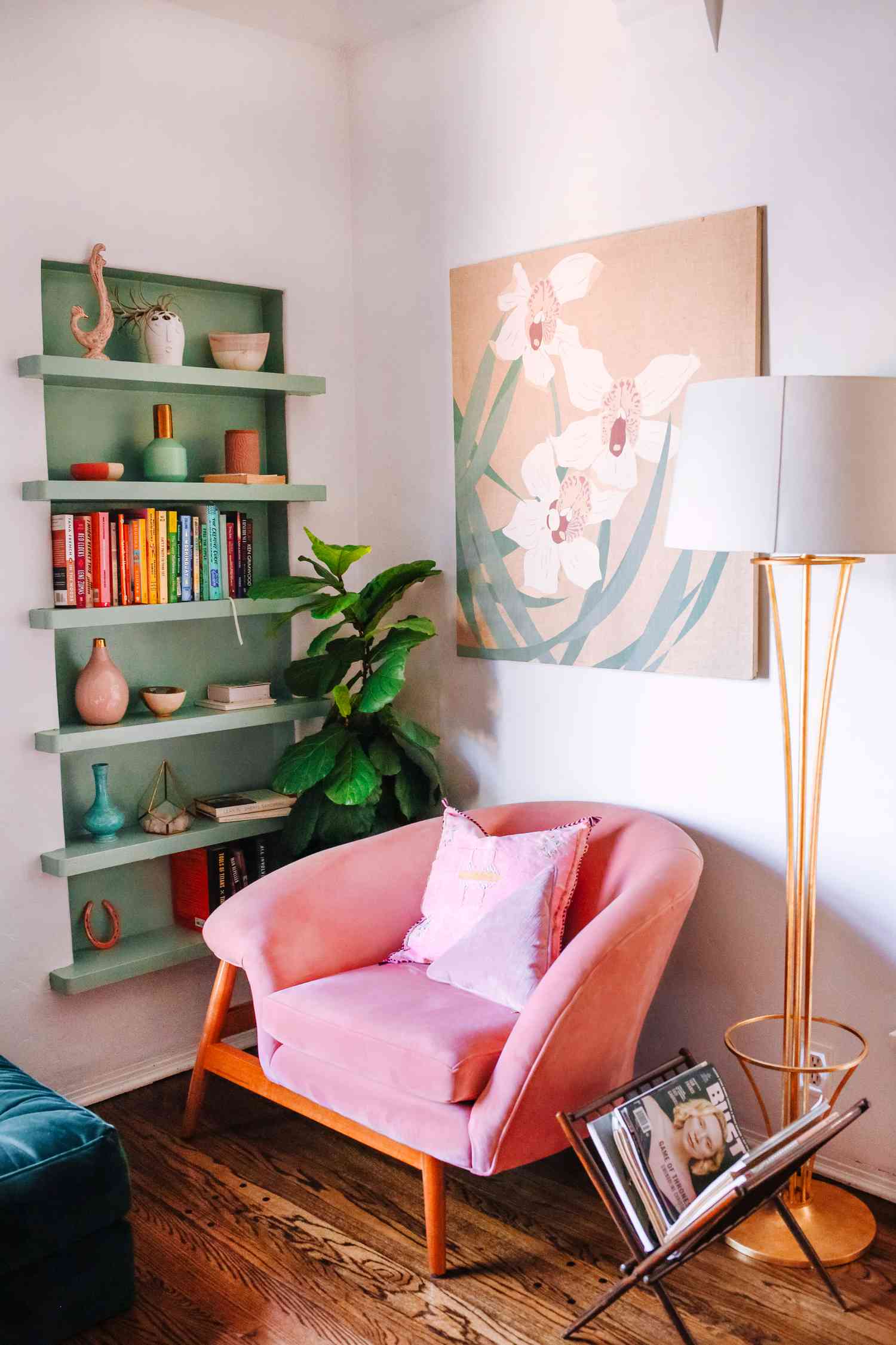 Un coin salon avec une chaise rose vif et une bibliothèque peinte en vert vif