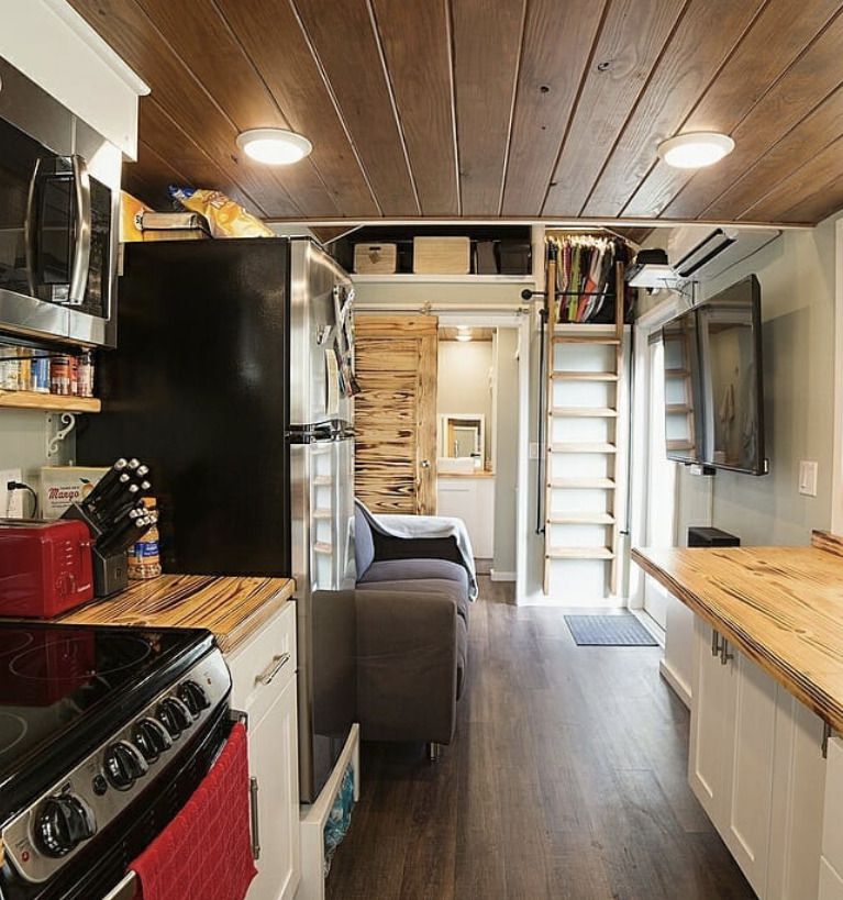 a tiny house kitchen with wood cabinets and full size appliances