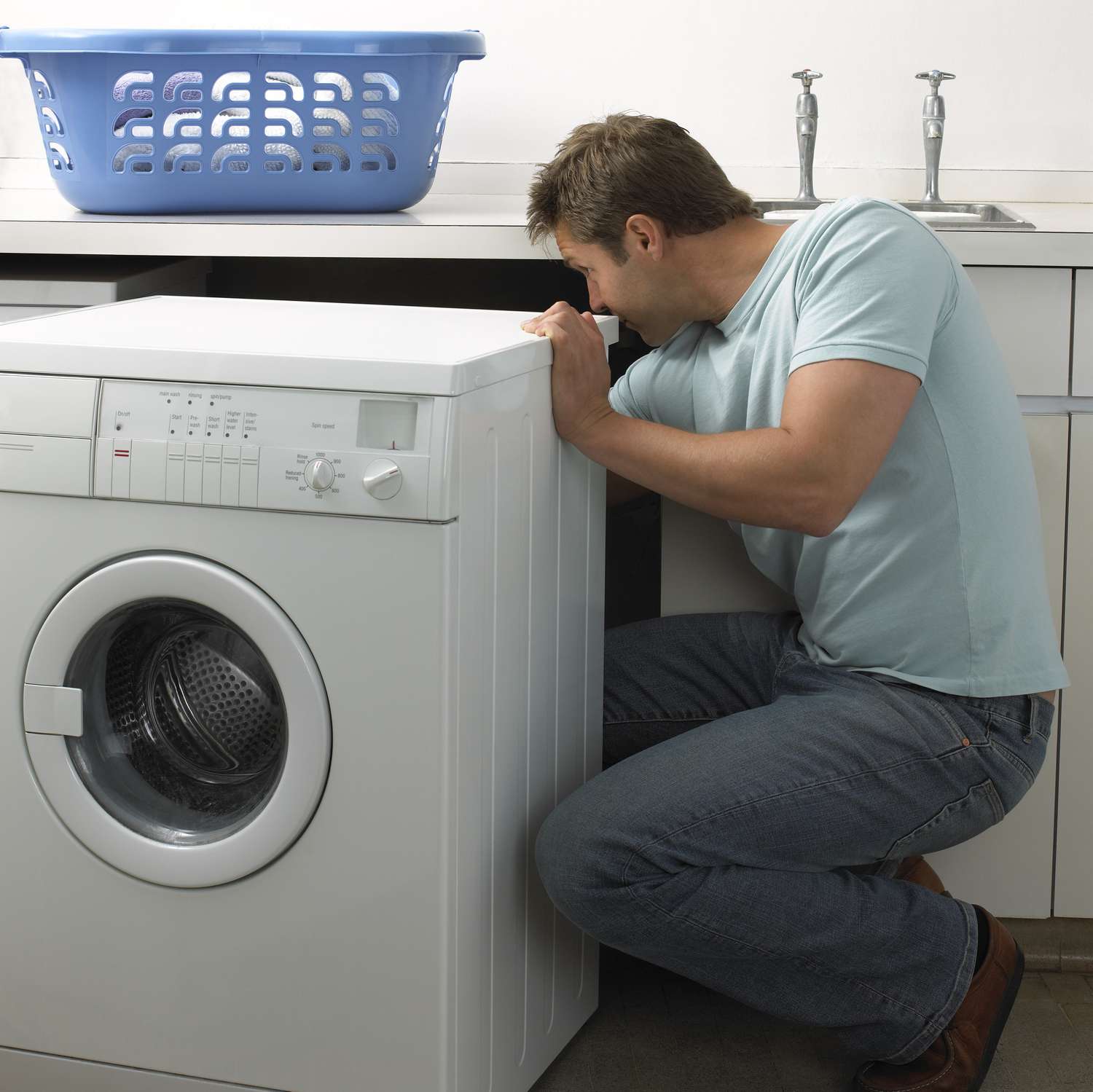 Homem em uma cozinha consertando uma máquina de lavar