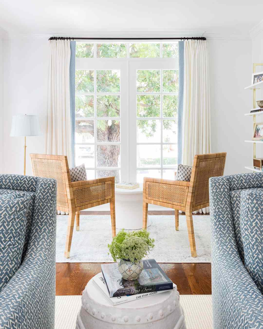 Un coin salon avec deux fauteuils en osier face à une grande fenêtre.