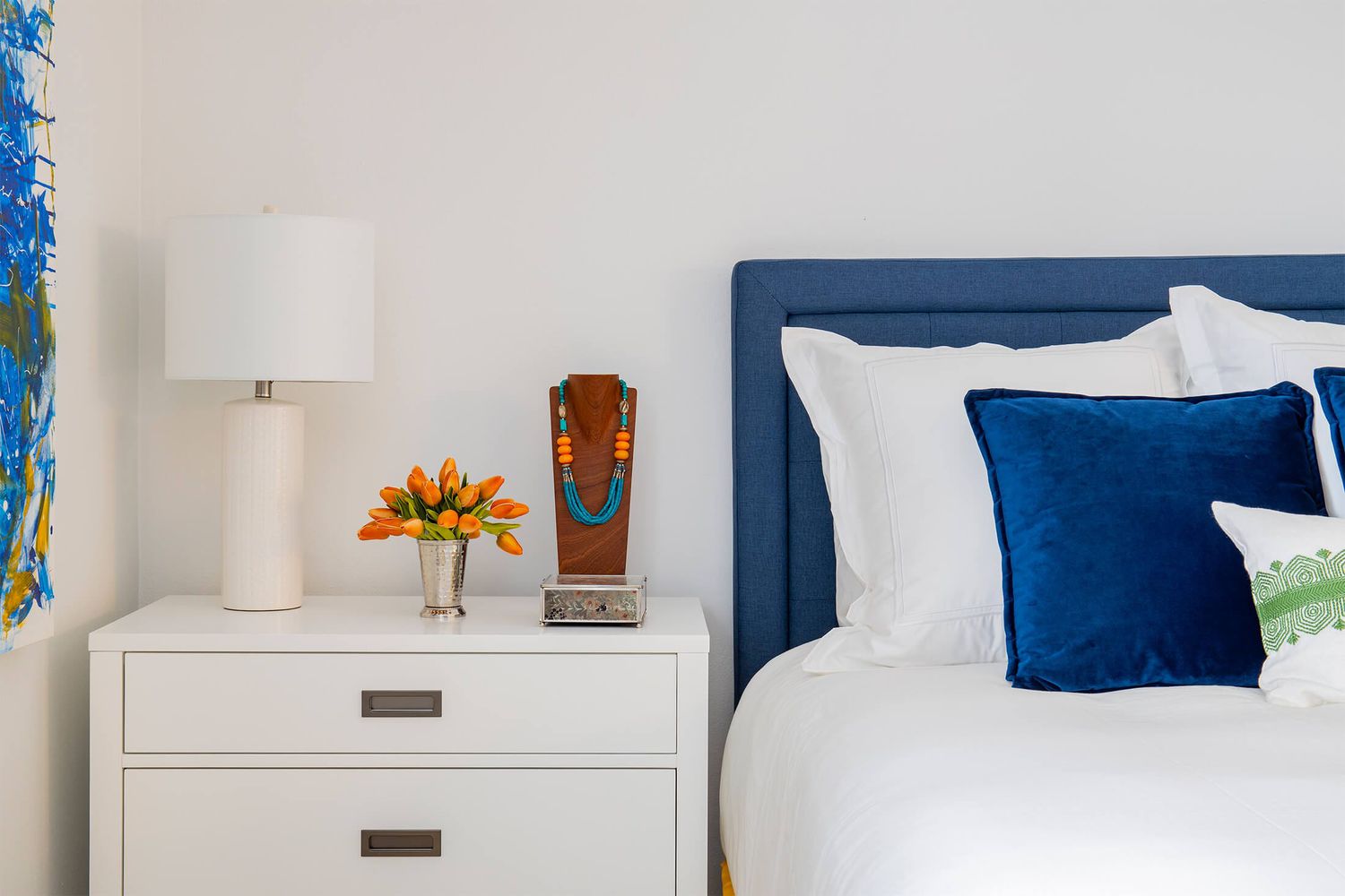 Blaues und weißes Schlafzimmer, kleiner Strauß oder orangefarbene Blumen auf dem Nachttisch