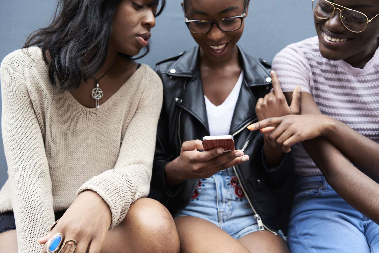 Three people looking a cell phone screen