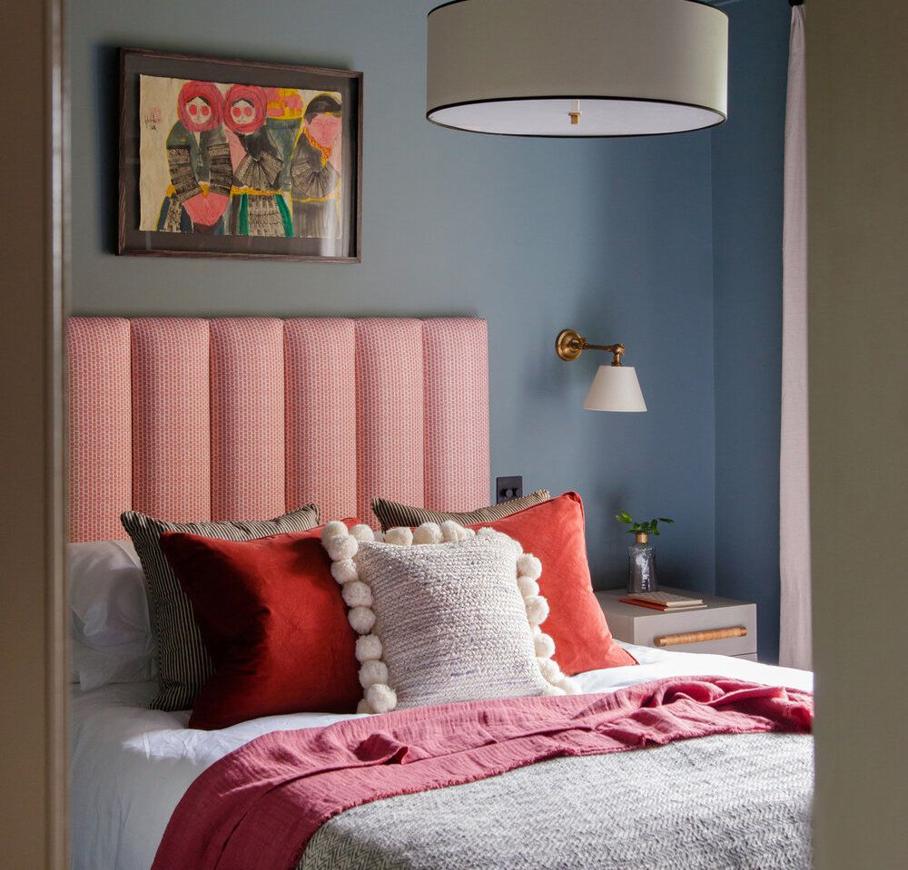 dormitorio con cabecero y almohadas rojas, paredes azul aciano