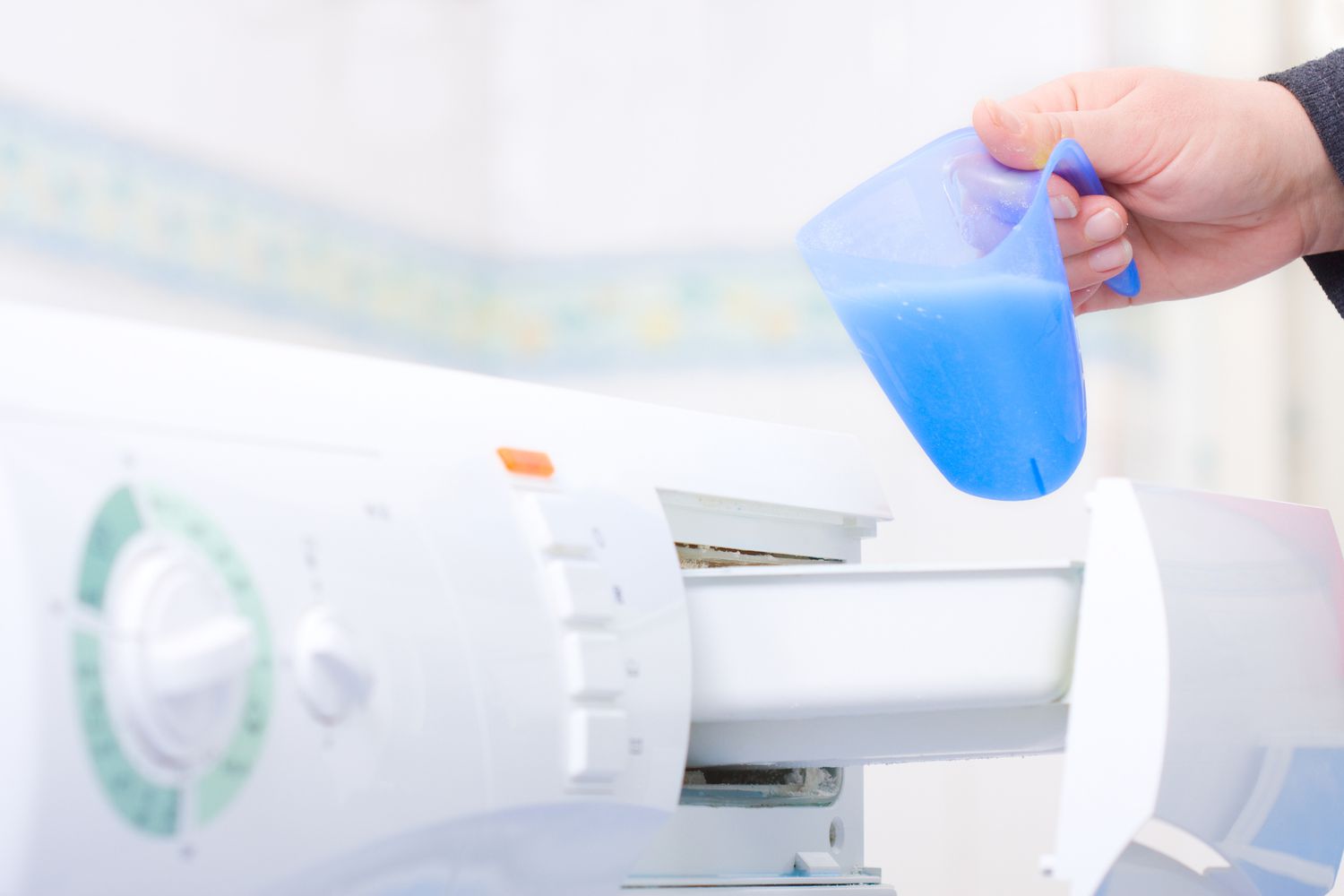 Una persona vierte detergente en una lavadora