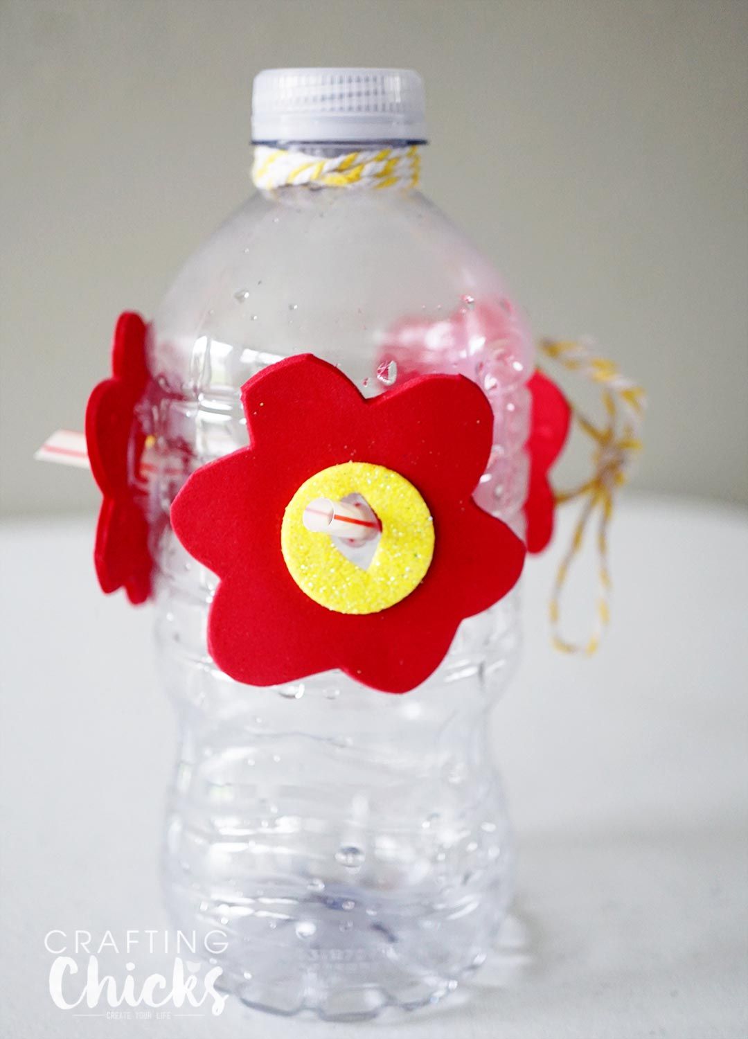 Una botella de plástico con flores de espuma rojas y amarillas