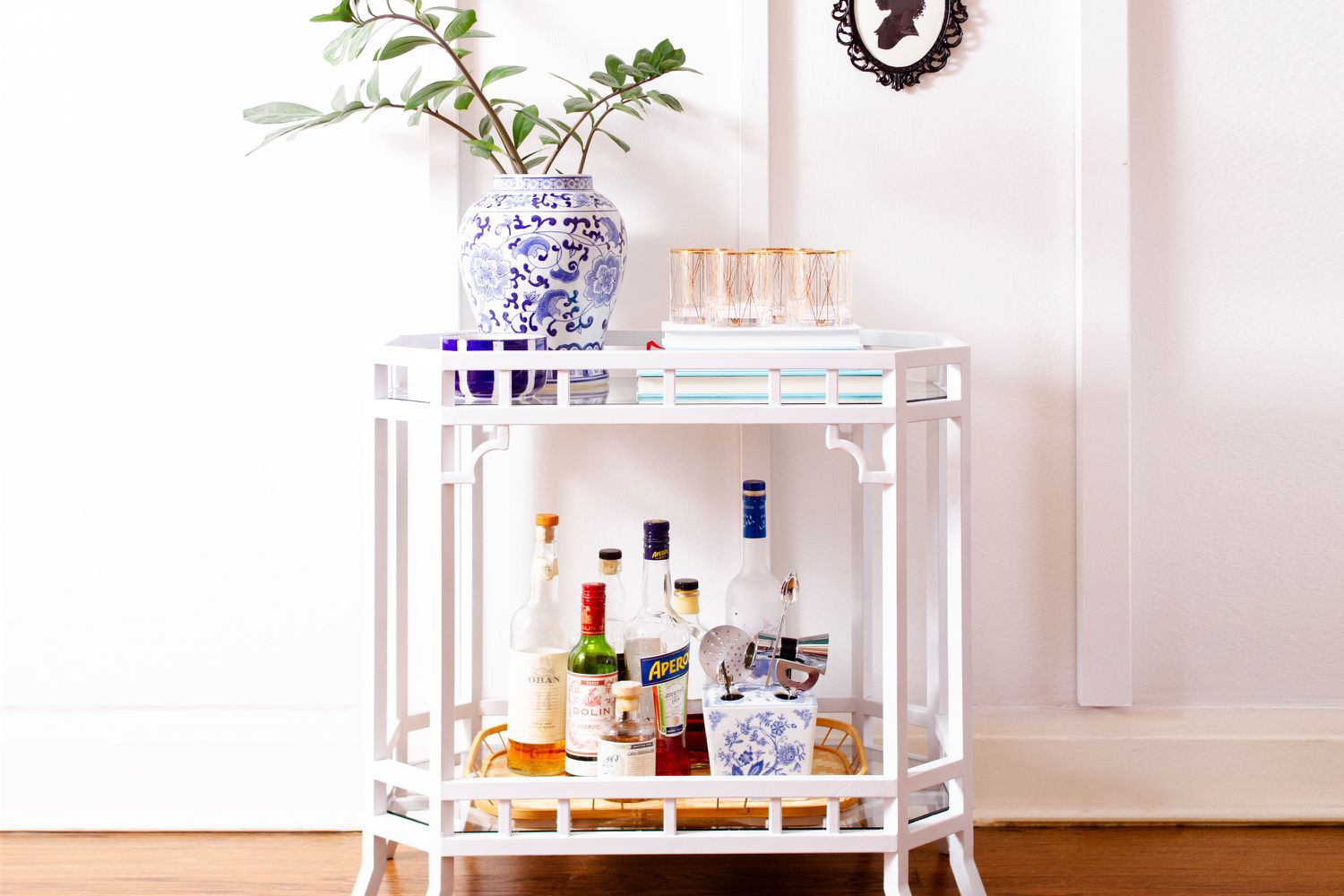 Weiße Mini-Bar, dekorative Vase und Tassen über Schnapsflaschen