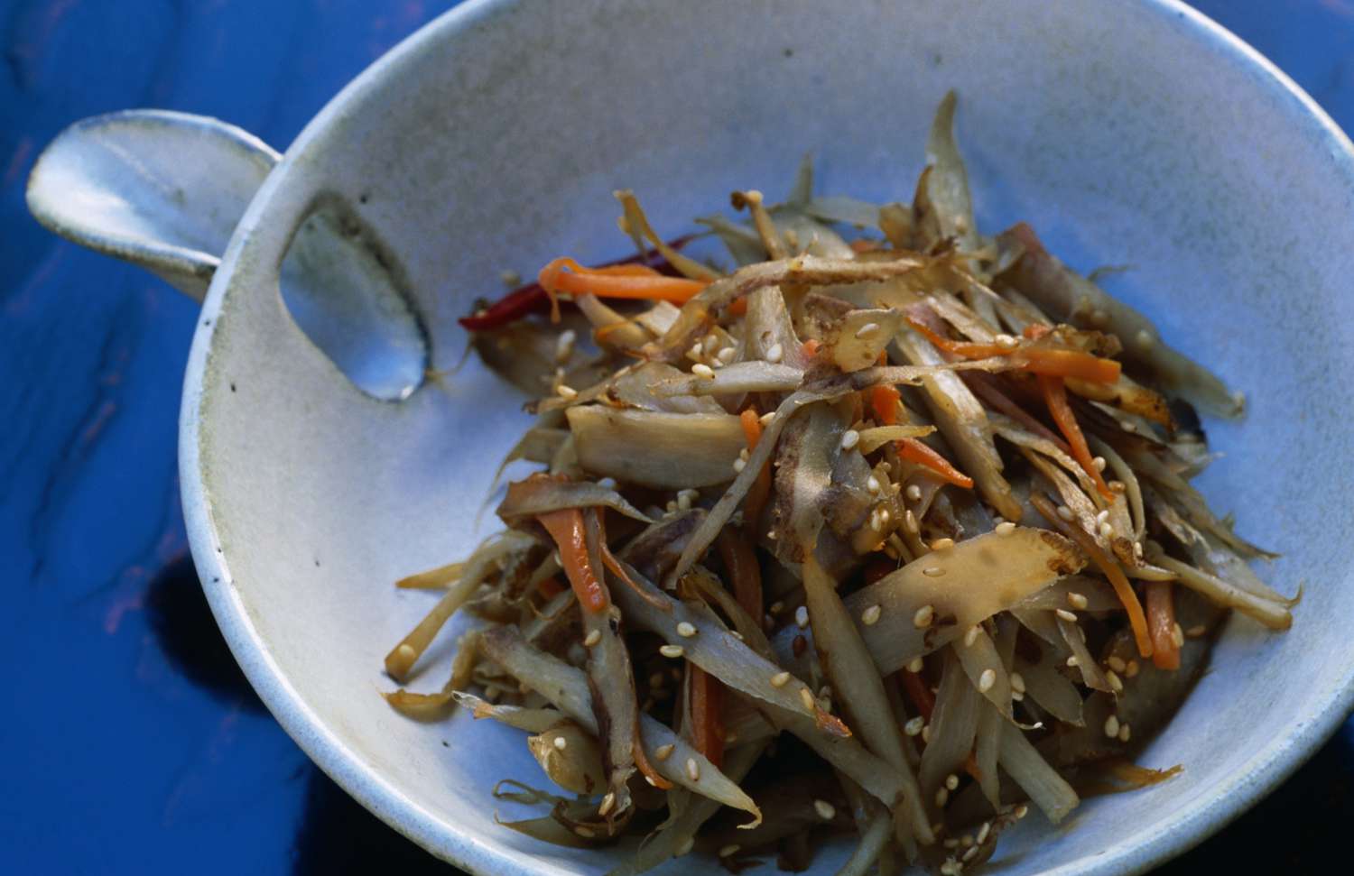 Kimpira gobo ((geschmorte Klette), in Stäbchen geschnitten und frittiert, mit Karotte und als Beilage gegessen
