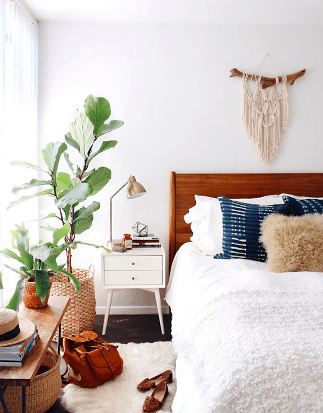 Quarto Boho com edredom branco e plantas.