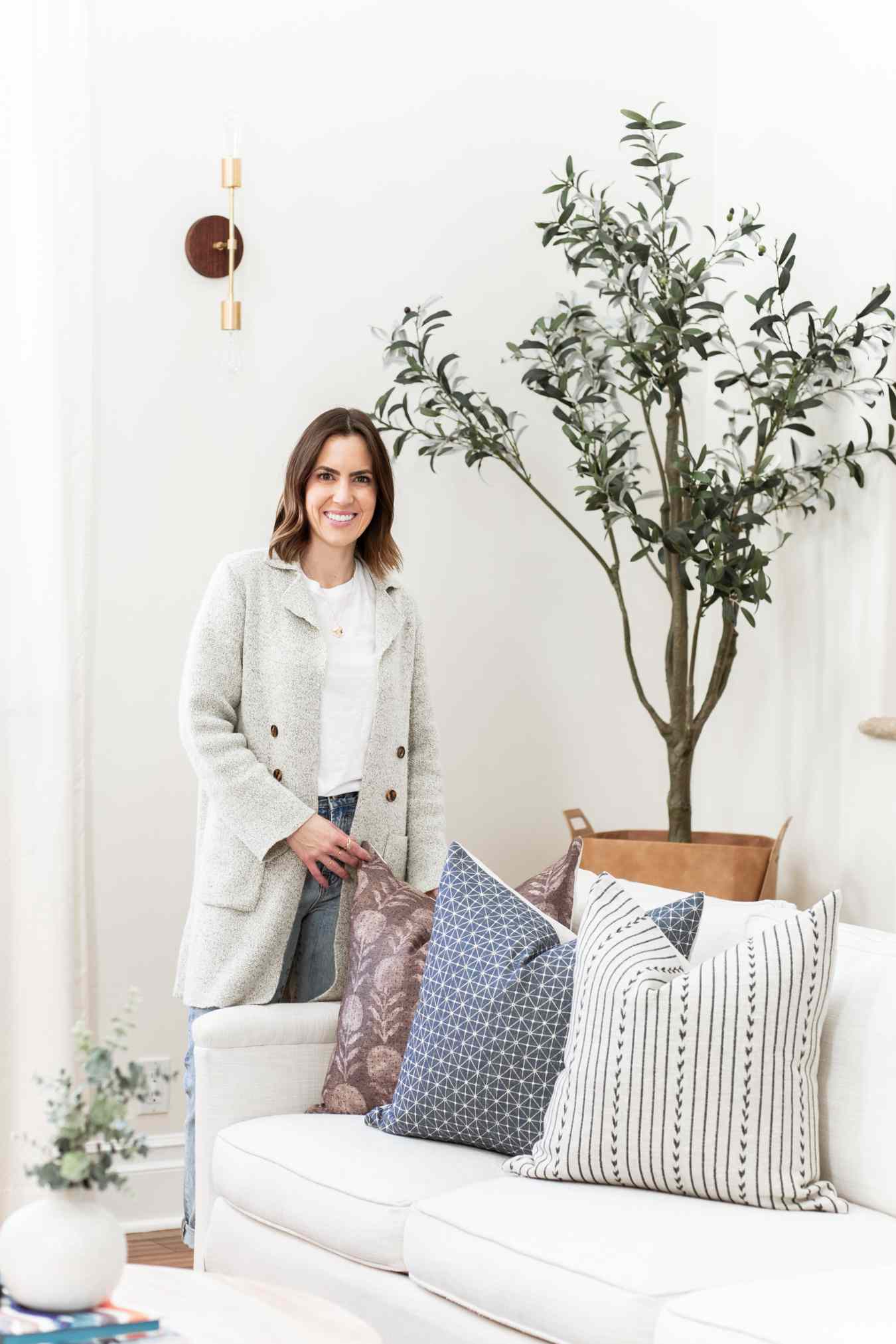 Lauren Meichtry posiert in einem Zimmer neben einer Pflanze und einer Couch