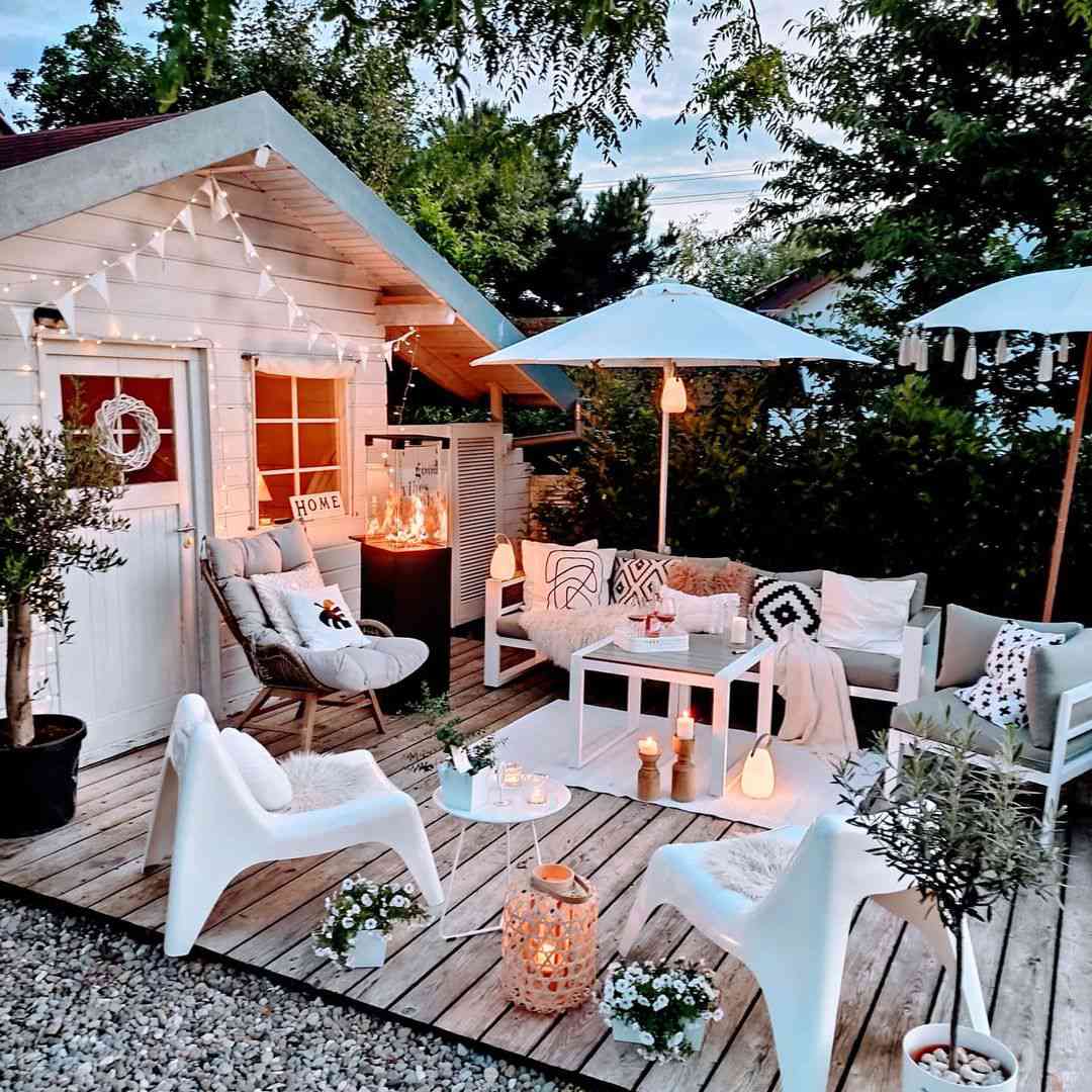 Ein Schuppen mit einer gemütlichen Outdoor-Lounge mit Stühlen und Kerzen.