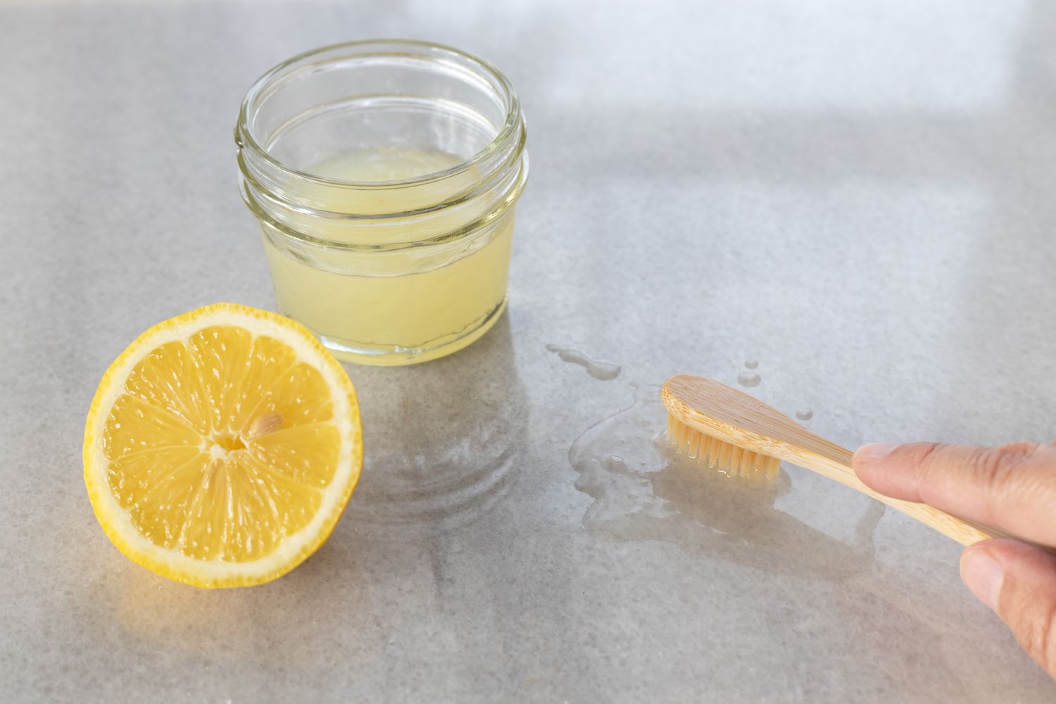 Tranche de citron à côté du récipient en verre de jus de citron et brosse à dents en bois frottant super glue 