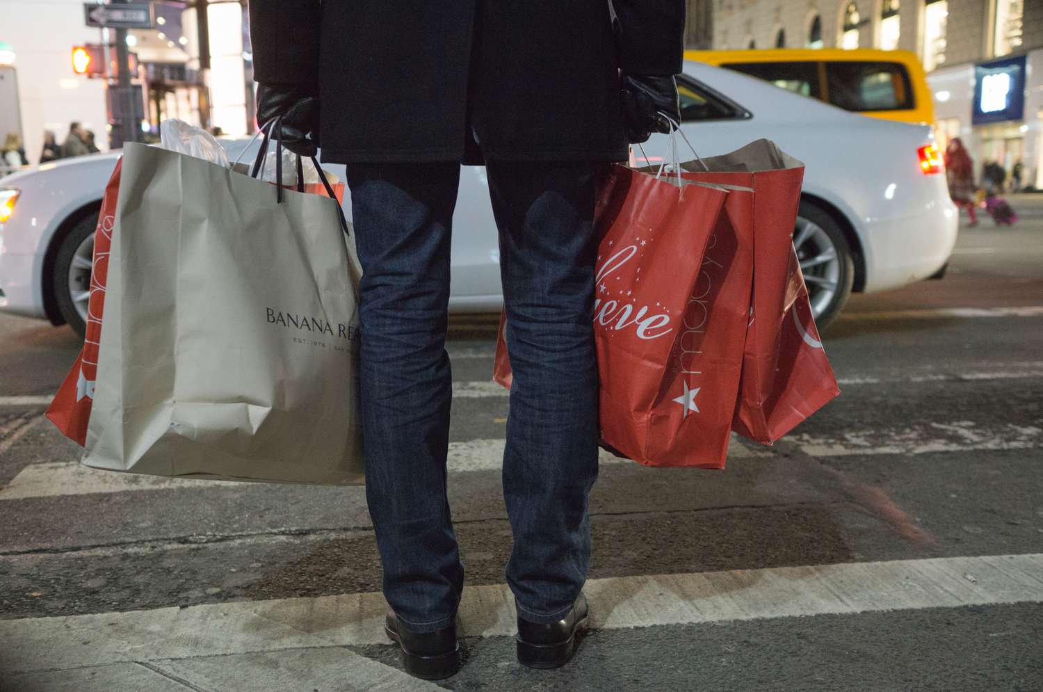 Ein Mann trägt Einkaufstüten am Schwarzen Freitag