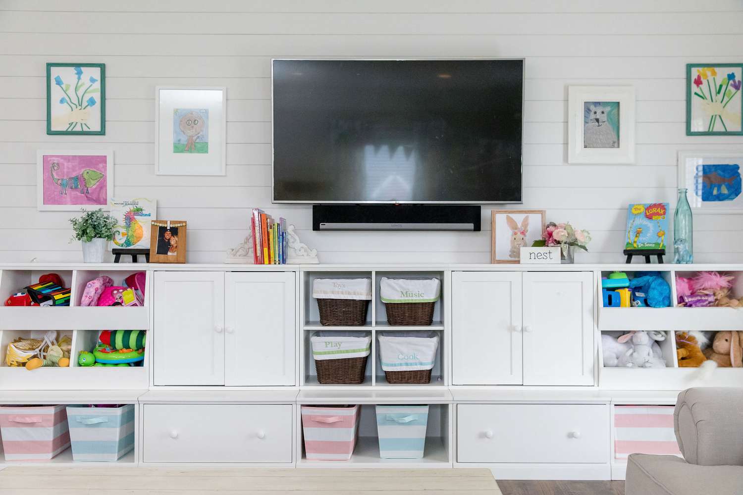 Sala de juegos en color con armarios blancos y televisor de pared de Jenny Reimold