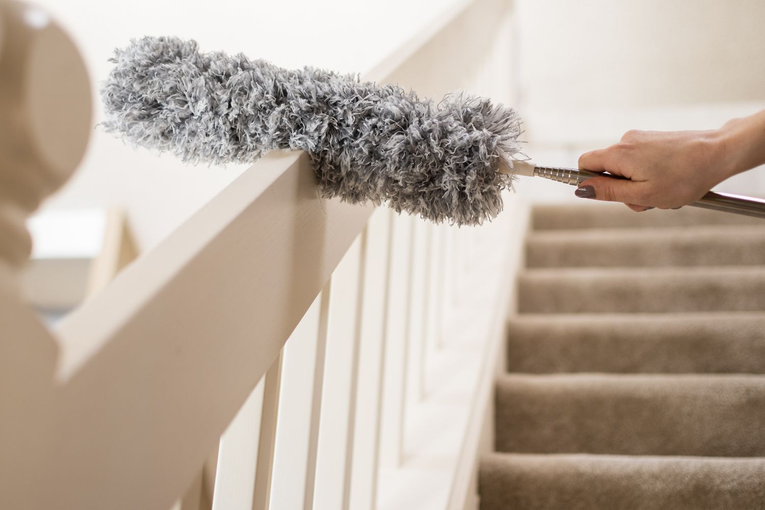 Long duster wiping staircase banister