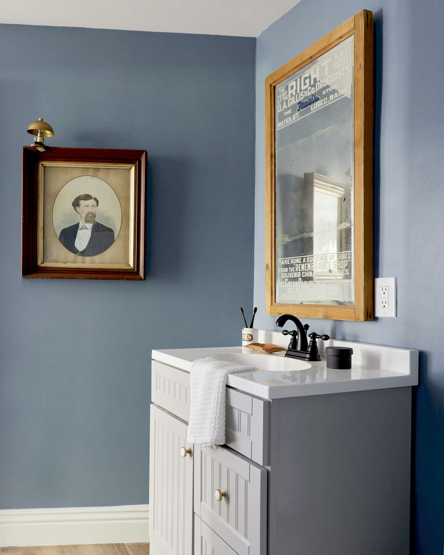 Blue bathroom mirror and sink with wall art