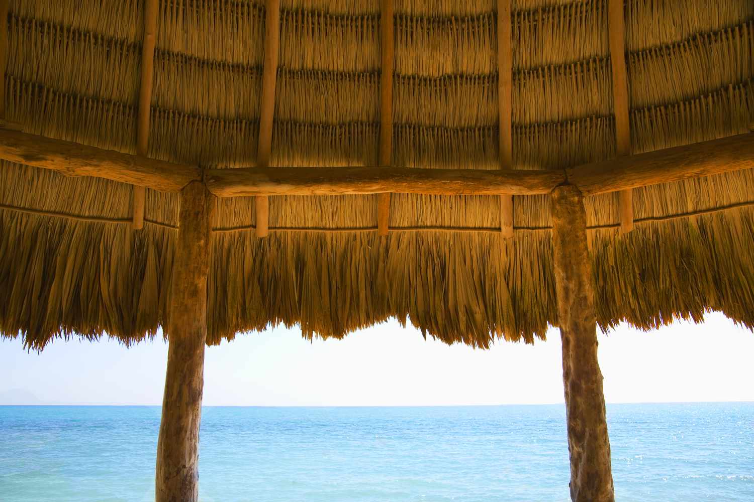 Strohdach einer Cabana mit Blick auf den Ozean.