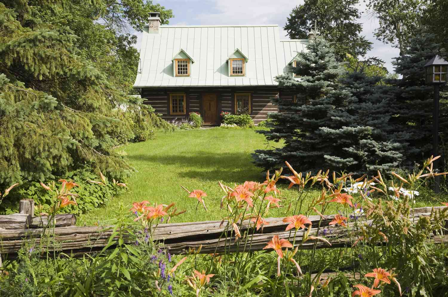 Casa rústica, con valla rústica y plantaciones en primer plano.