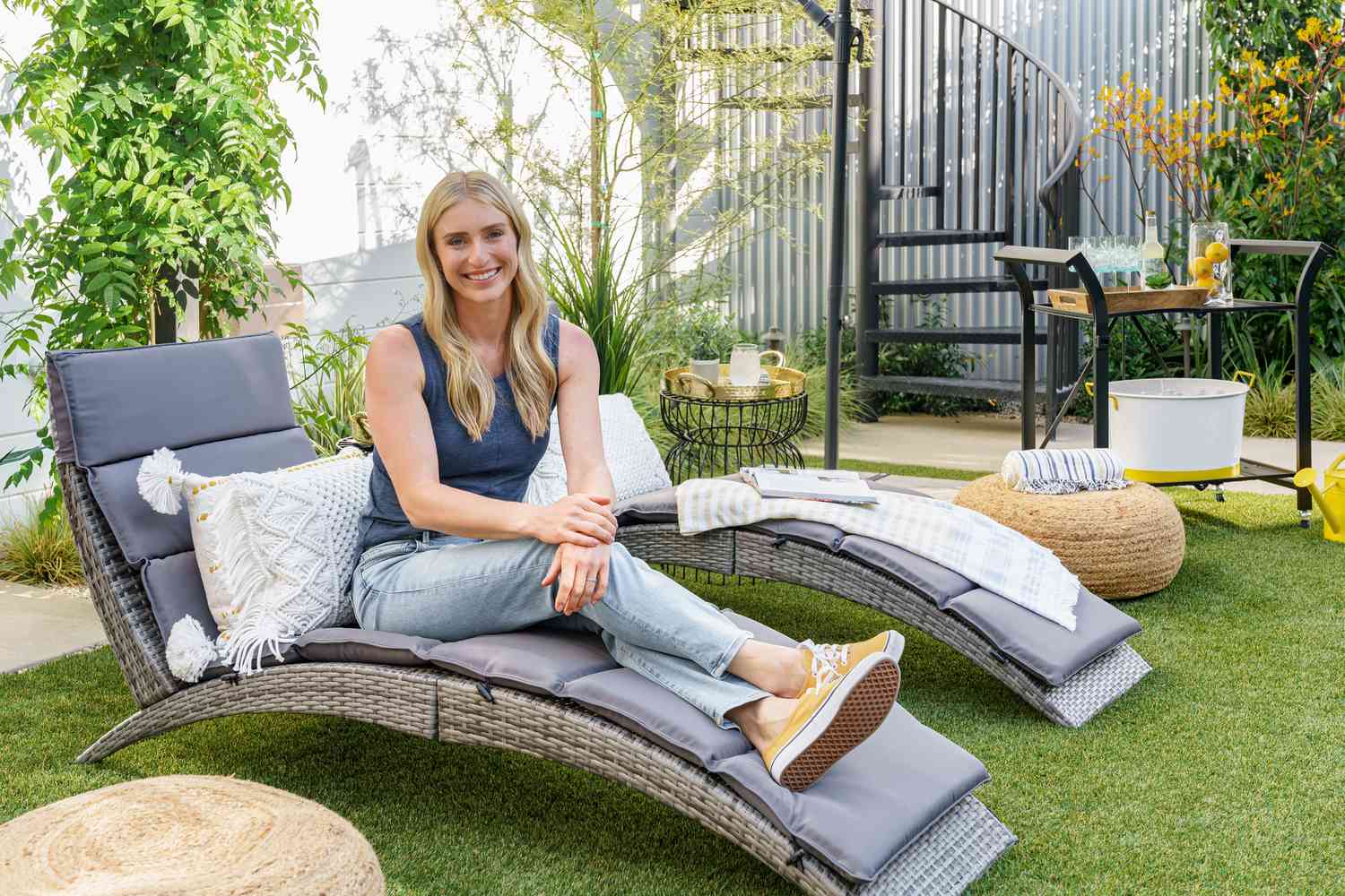 La estrella de HGTV Jasmine Roth posa en una tumbona plegable de ratán sintético en su patio trasero