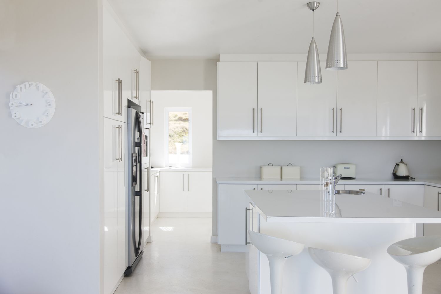 Moderne weiße und saubere Kücheneinrichtung mit Hockern am Tresen