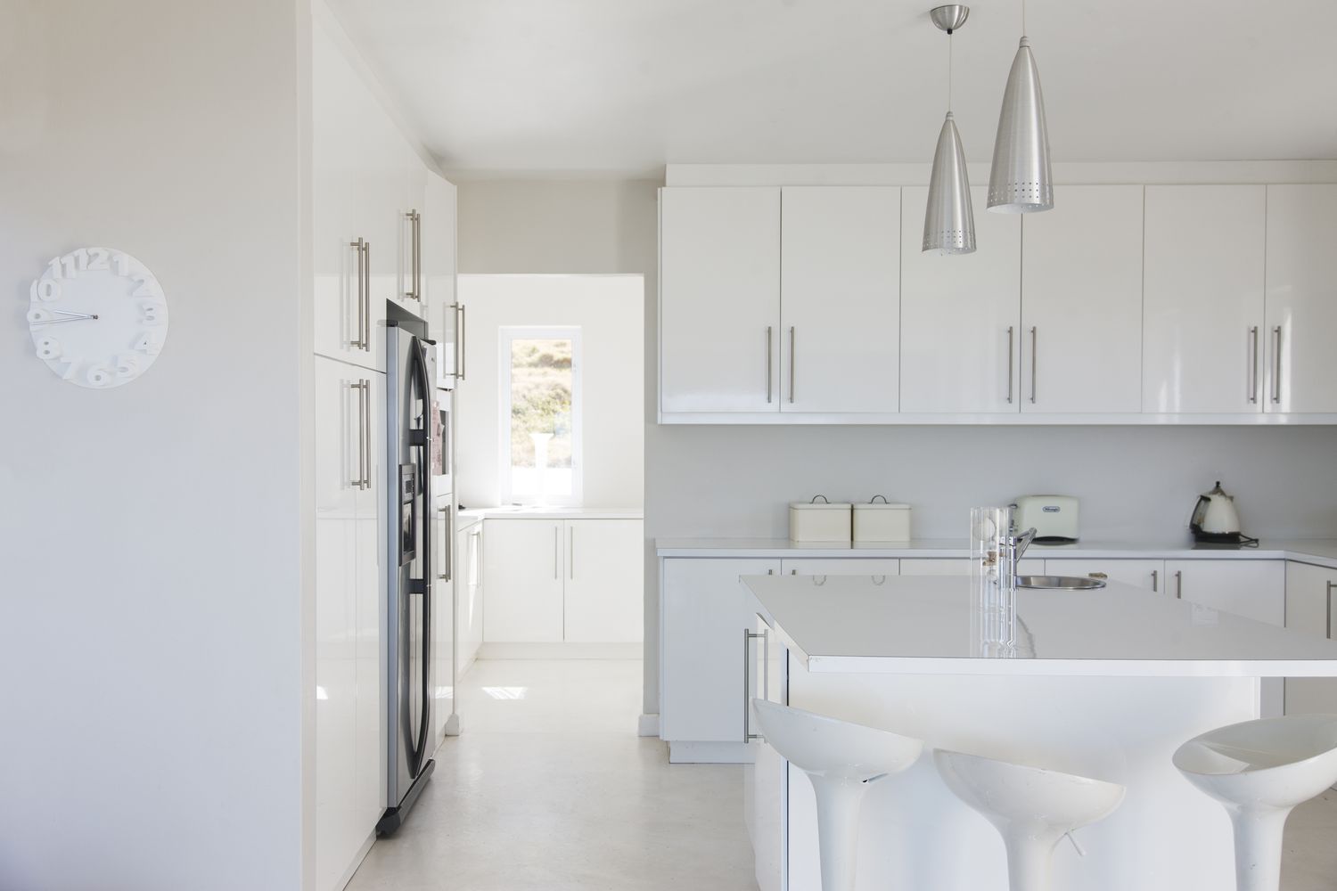 Interior de cocina moderna blanca y limpia con taburetes en la encimera