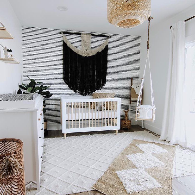 Quarto de bebê preto, branco e boho com peça focal dramática pendurada na parede