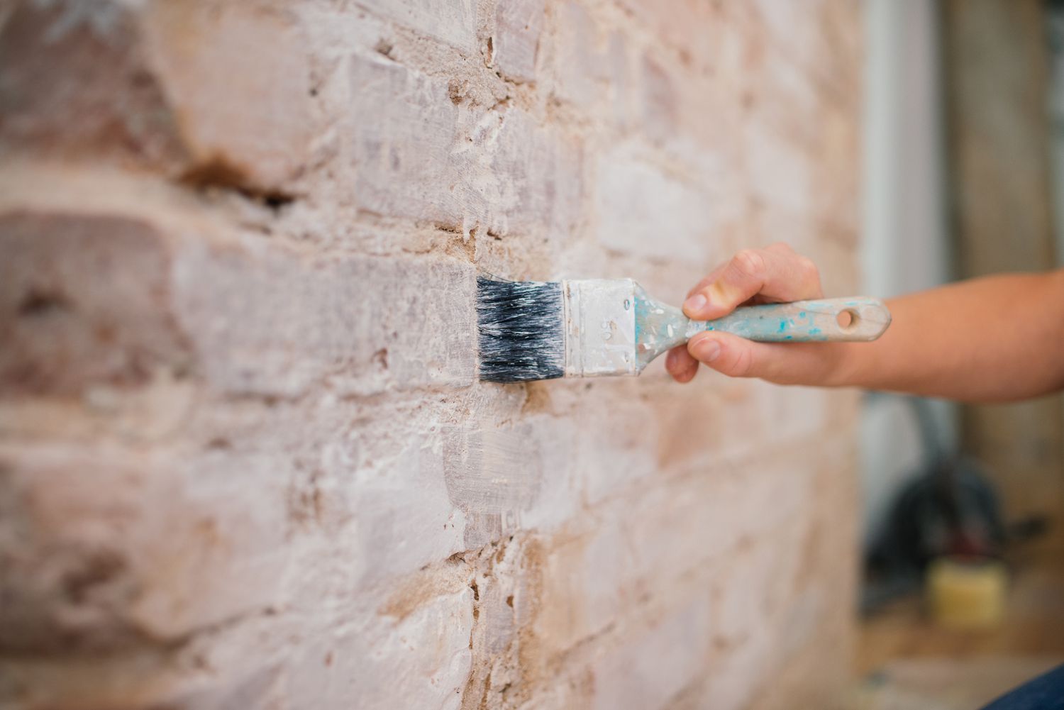 Woman painting brick wall