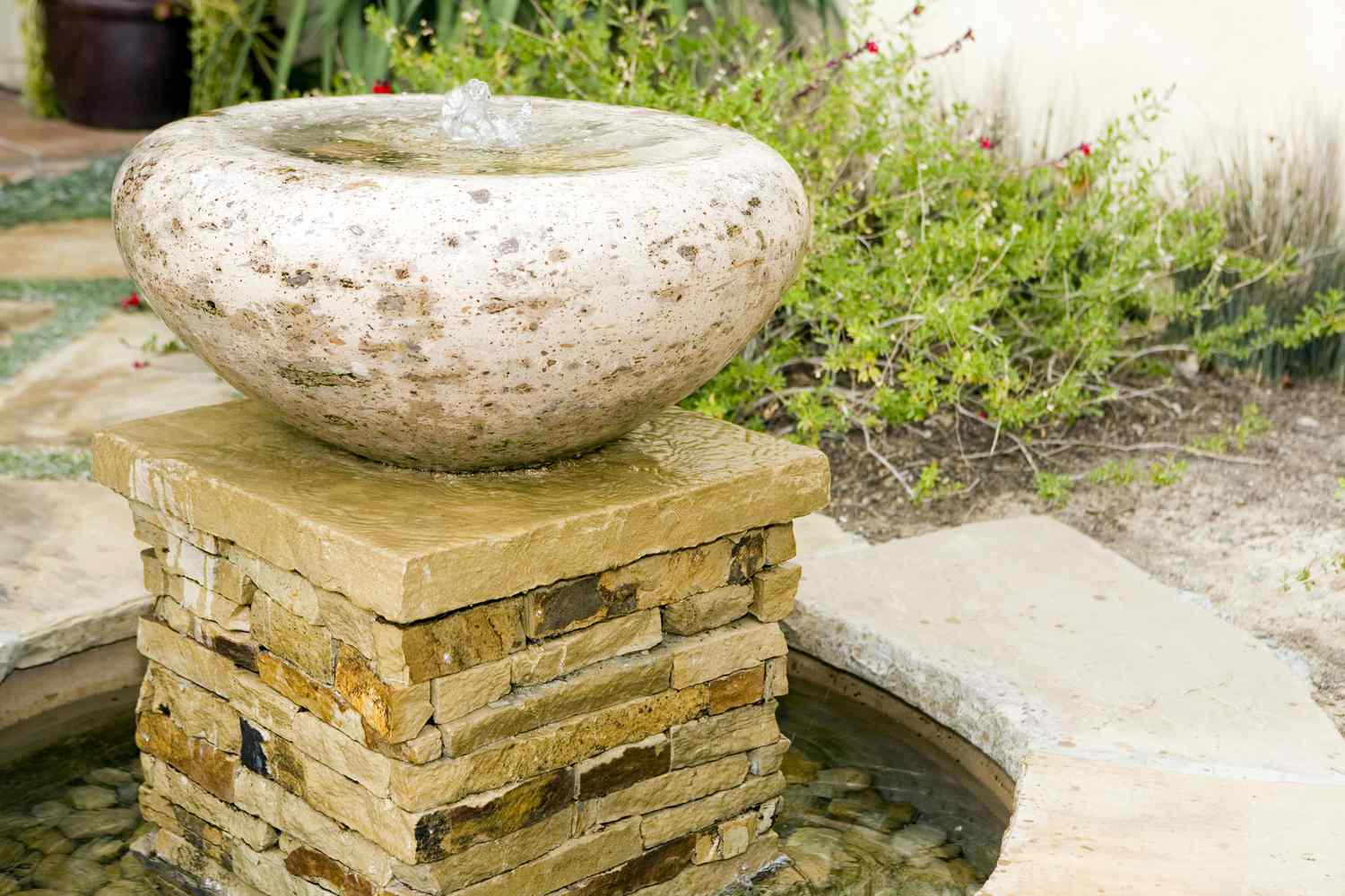 Fuente de piedra en patio con plantas.