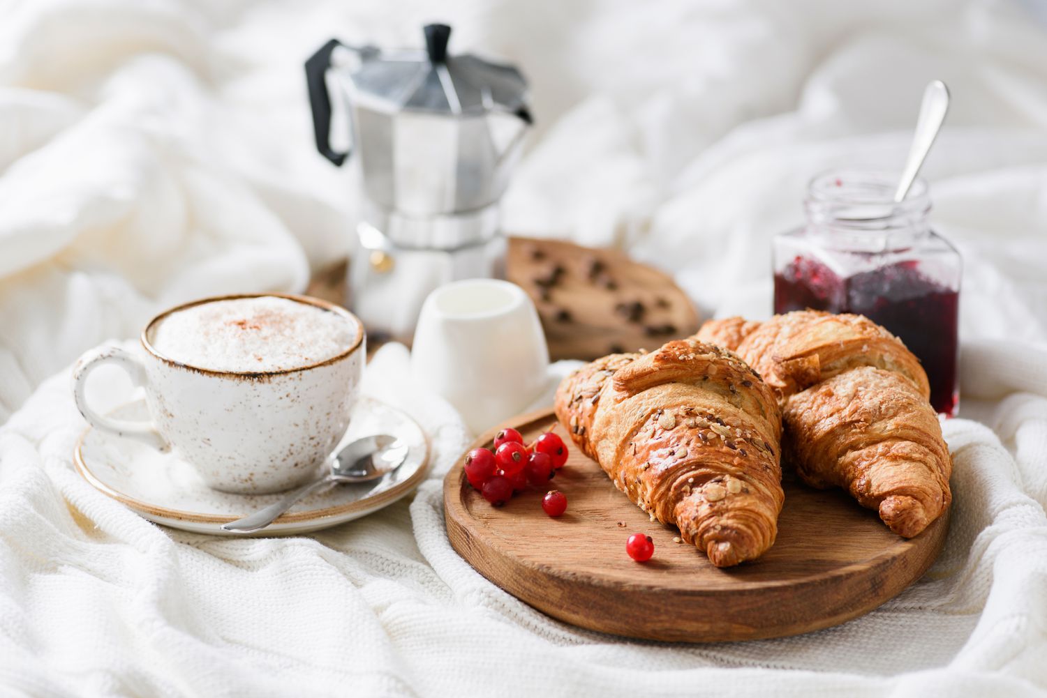 Frühstück im Bett mit Croissants, Kaffee und Marmelade