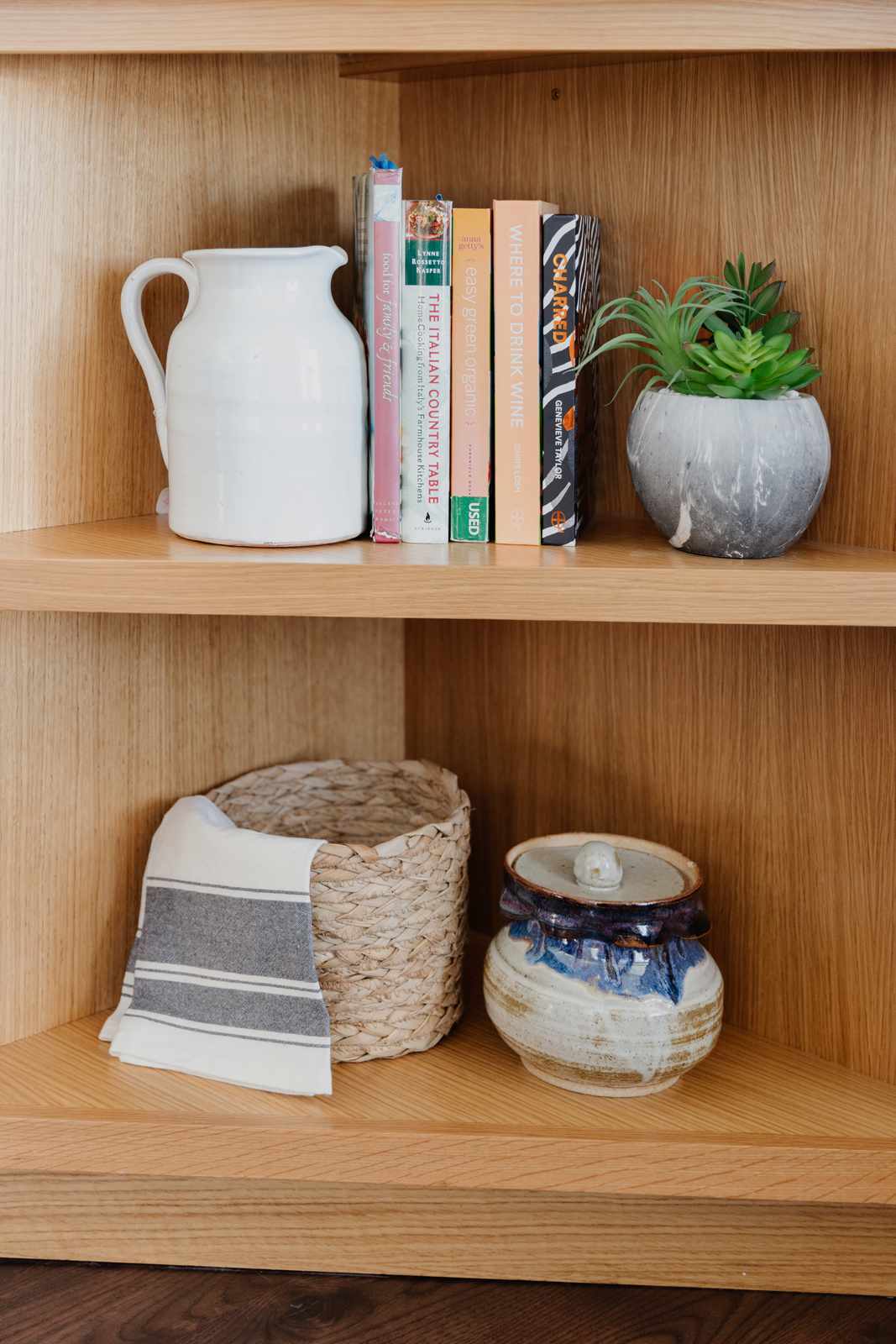 étagère d'angle en bois avec livres de cuisine, plante, et autres petits objets de décoration