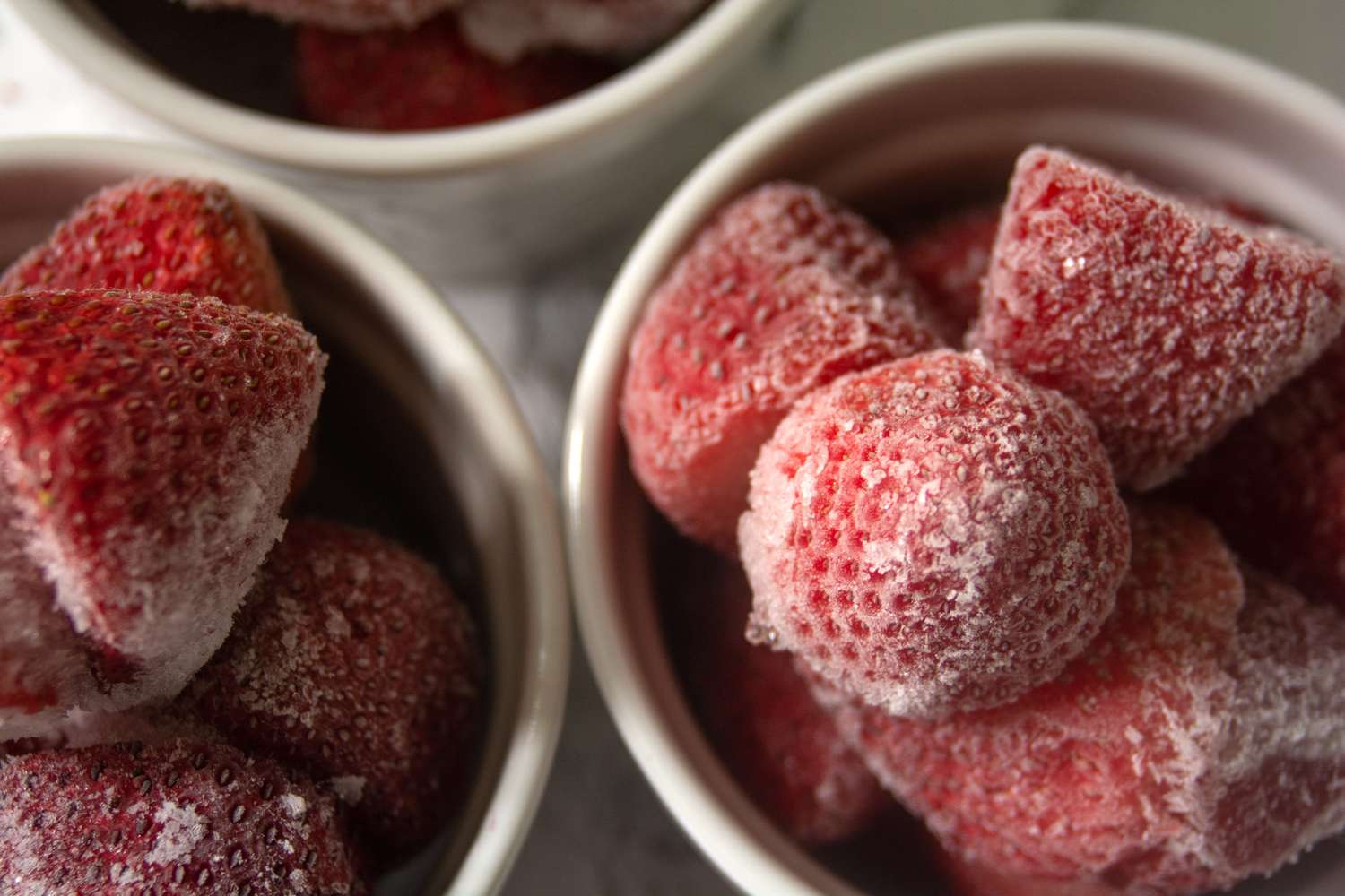 Harvested frozen strawberries clustered in small bowls closeup 