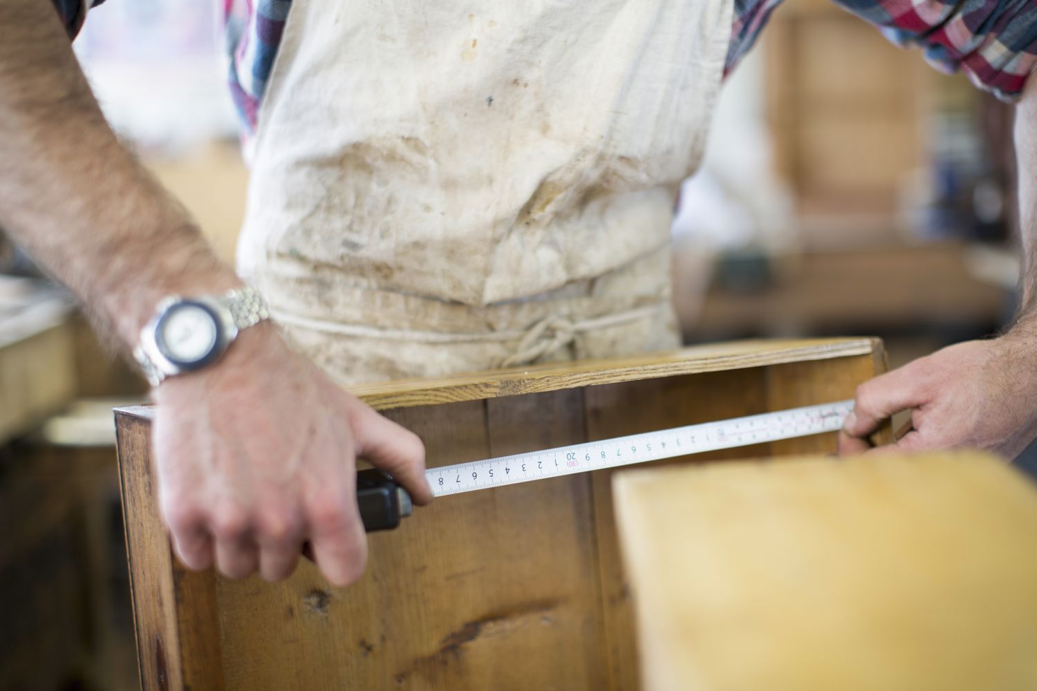 Um restaurador de móveis antigos medindo uma peça de madeira.