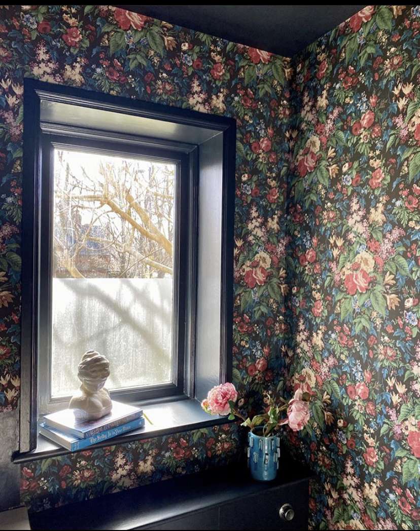 Sala com papel de parede floral e uma janela