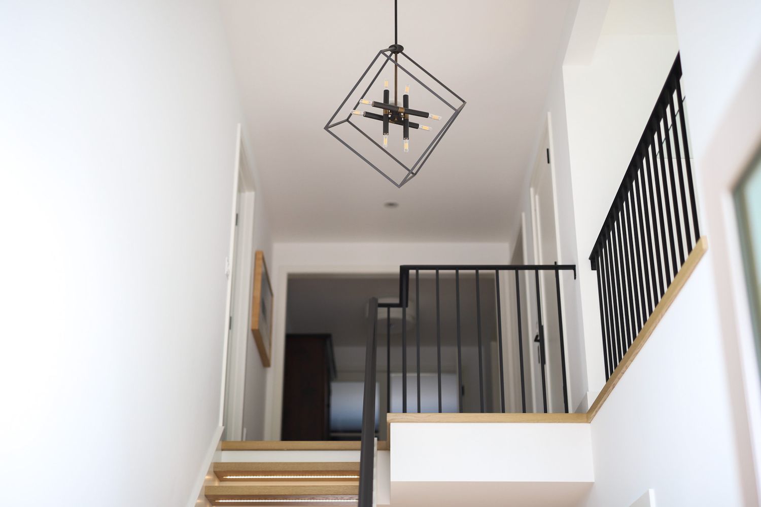 Foyer-Kronleuchter mit geometrischen Mustern über schwarzem Geländer neben der Treppe